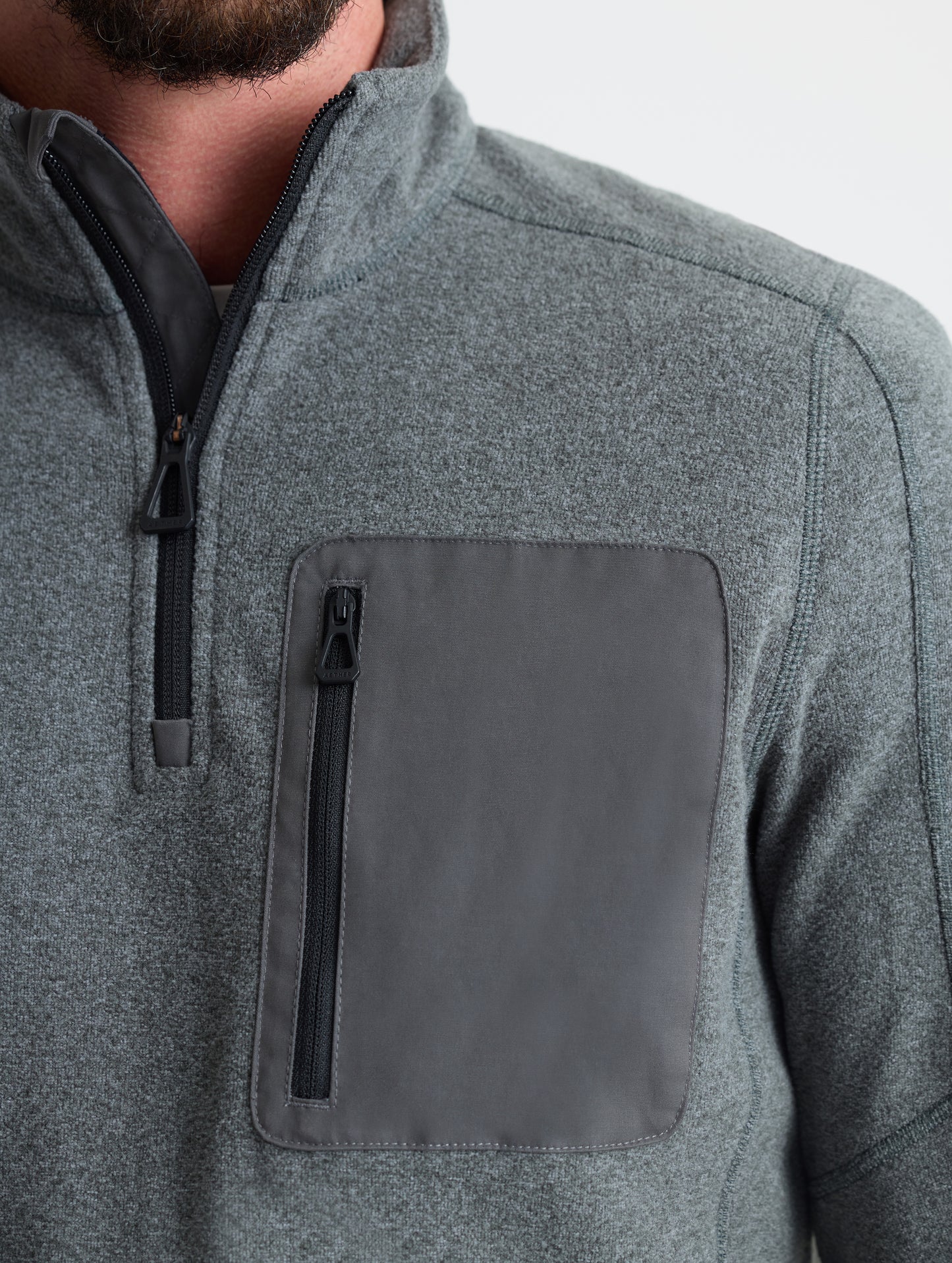 Closeup view of wearer's left shoulder and chest pocket of Sutherlin Half-Zip in Charcoal Heather from AETHER Apparel.