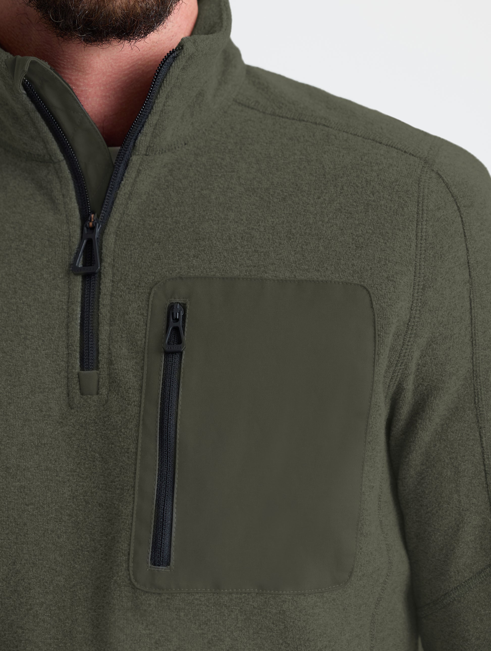 Closeup view of left shoulder and chest patch of Sutherlin Half-Zip in Forest Green from AETHER Apparel.