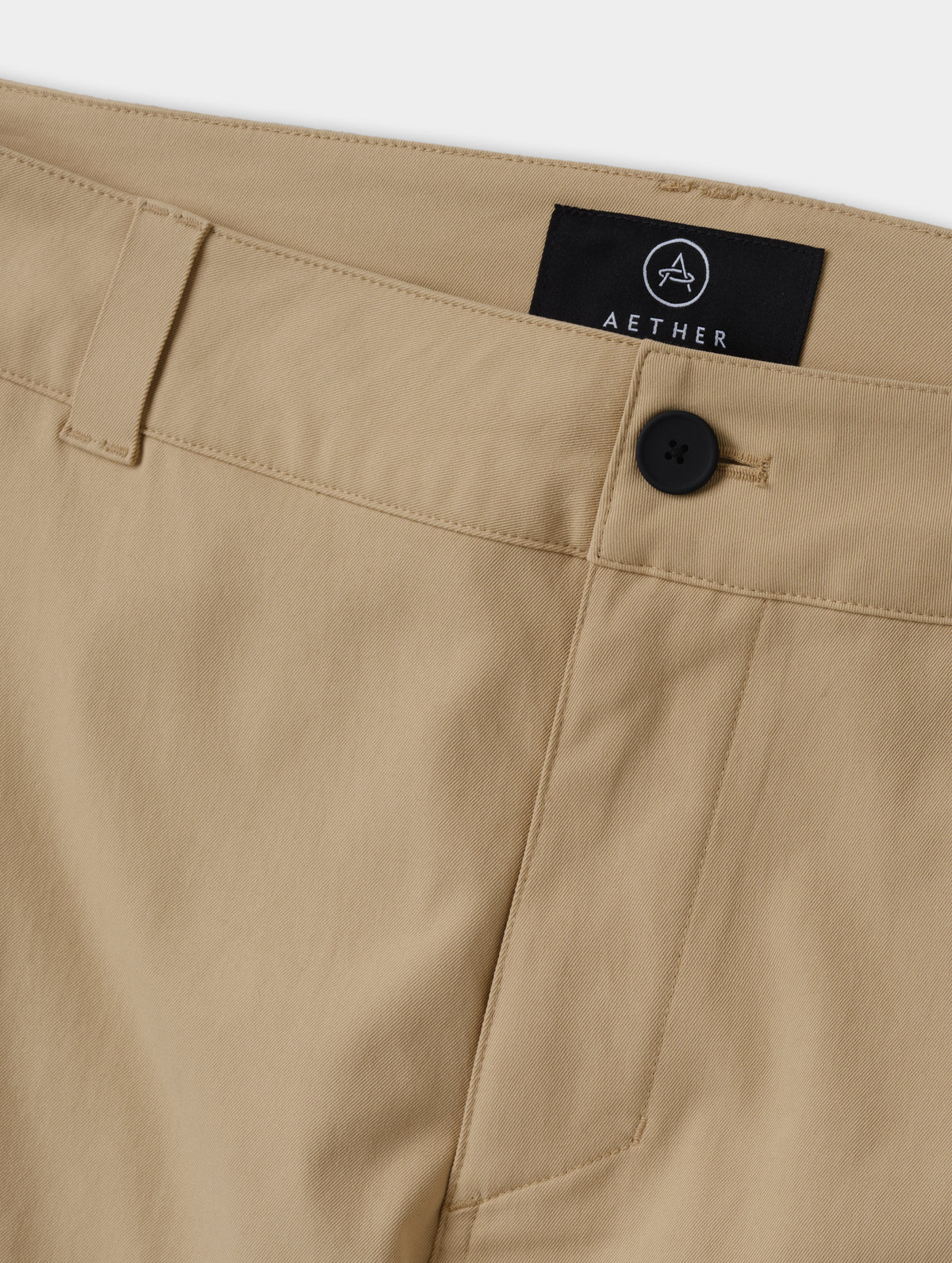 Closeup detailed view of the main center-front button closure and zipper fly on the Walden Tech Pant in Desert Tan from AETHER Apparel. 