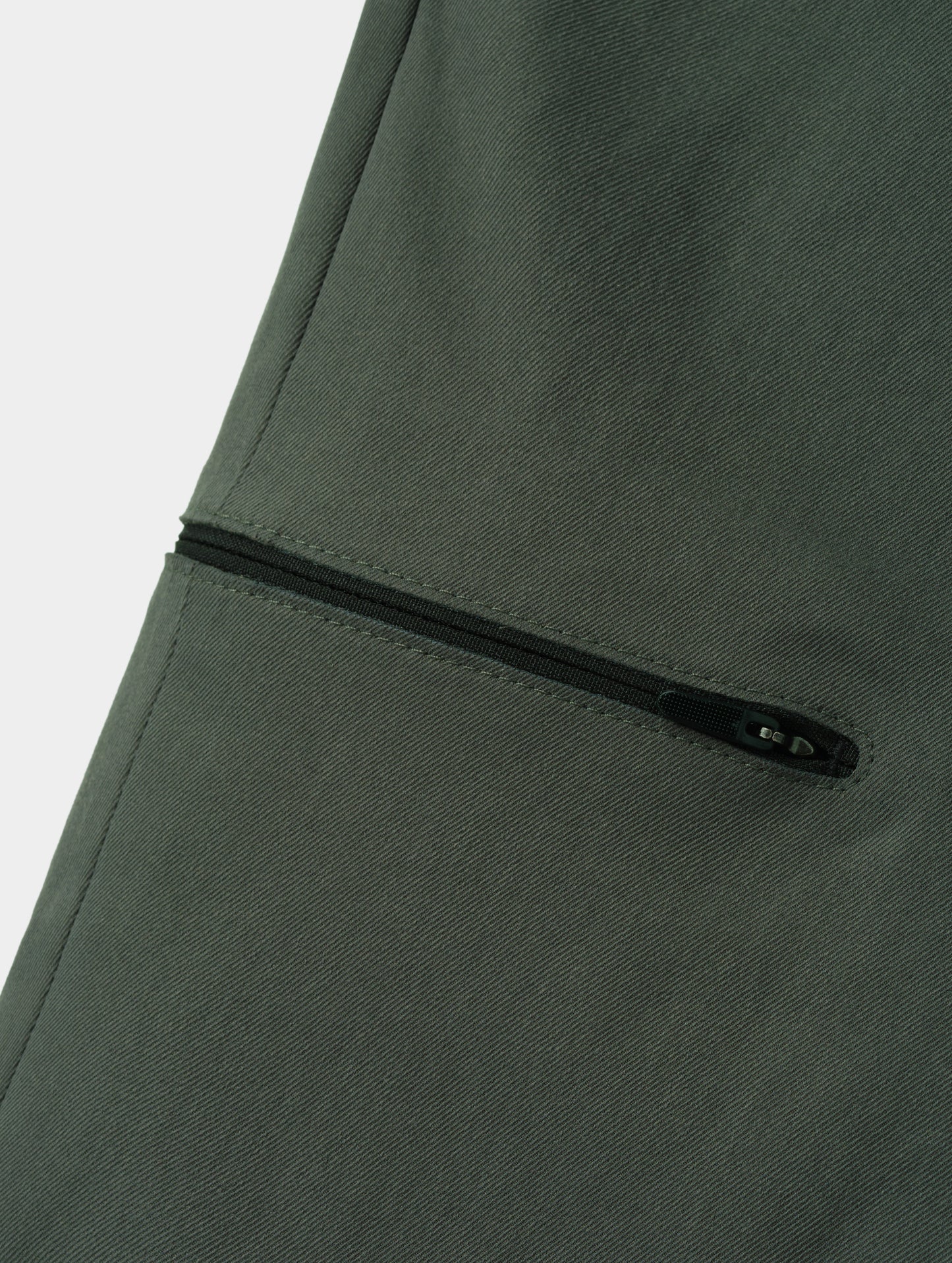 Closeup detailed view of the bonded zipper thigh pocket on the Walden Tech Pant in Saville Green from AETHER Apparel. 