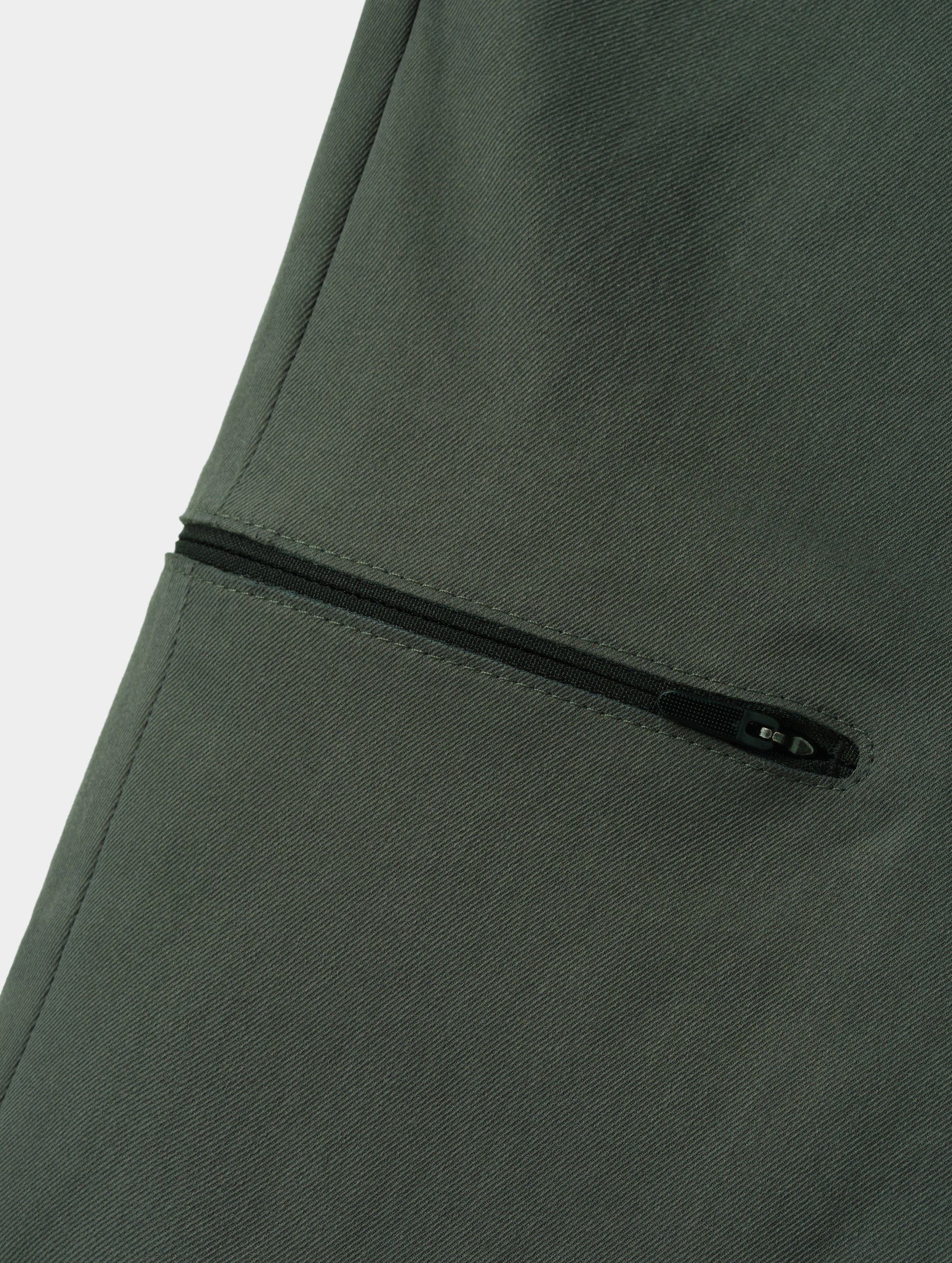 Closeup detailed view of the bonded zipper thigh pocket on the Walden Tech Pant in Saville Green from AETHER Apparel. 