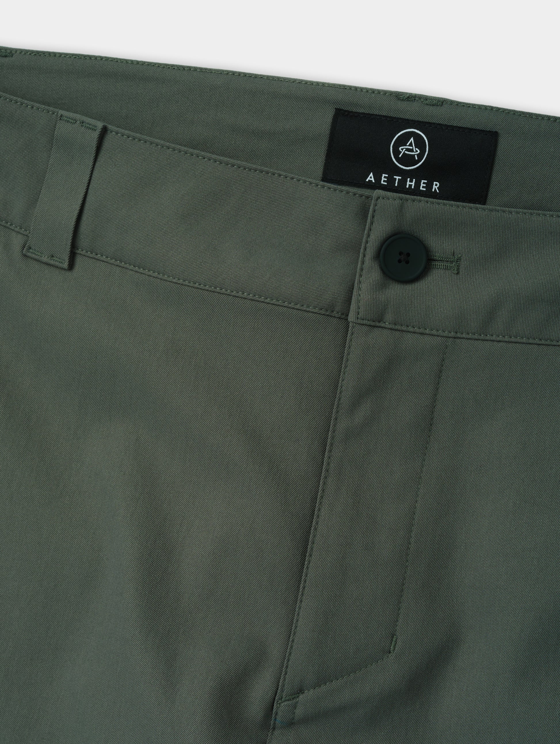 Closeup detailed view of the main center-front button closure and zipper fly on the Walden Tech Pant in Saville Green from AETHER Apparel. 