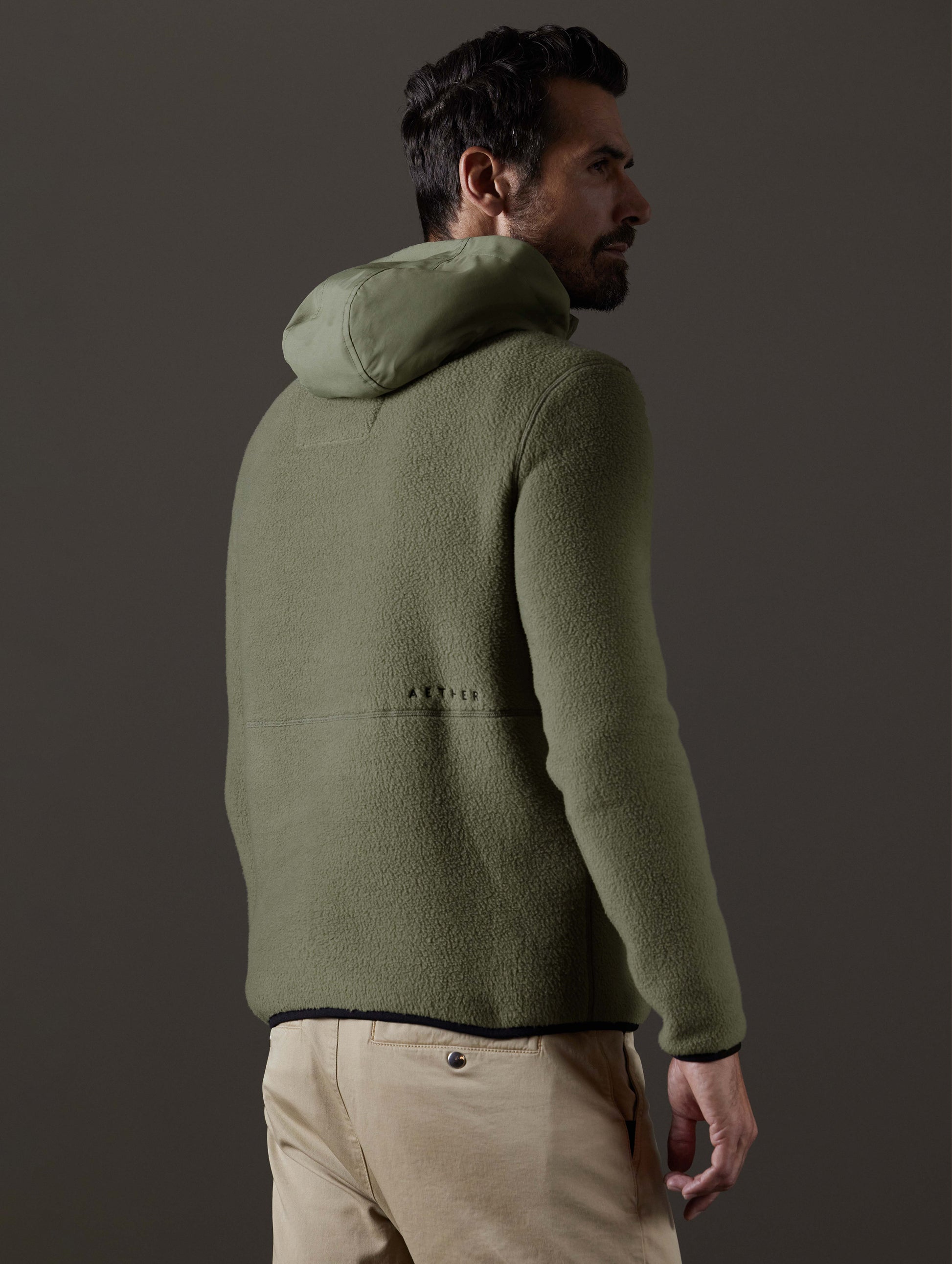 Rear 3/4 body view of man wearing Walsh Hooded Anorak in Fern Green from AETHER Apparel.