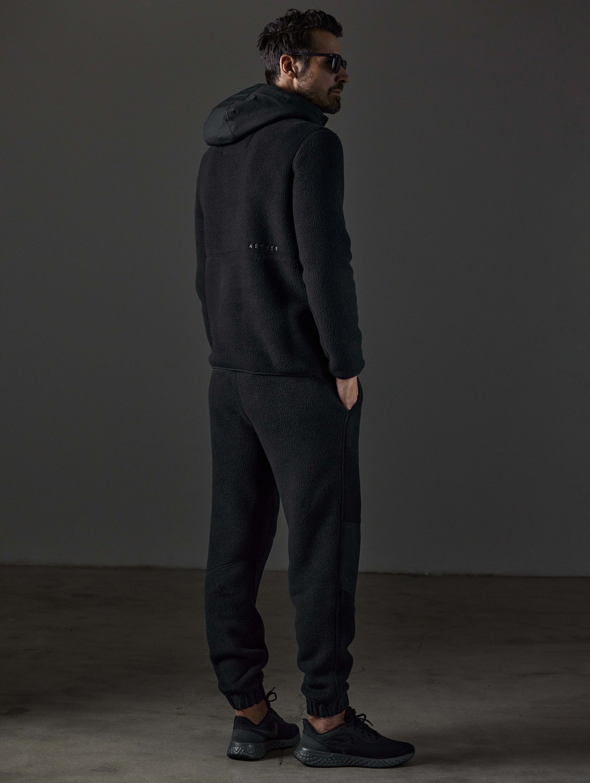 Rear 3/4 full-body view of man wearing Walsh Pant in Onyx Black from AETHER Apparel.