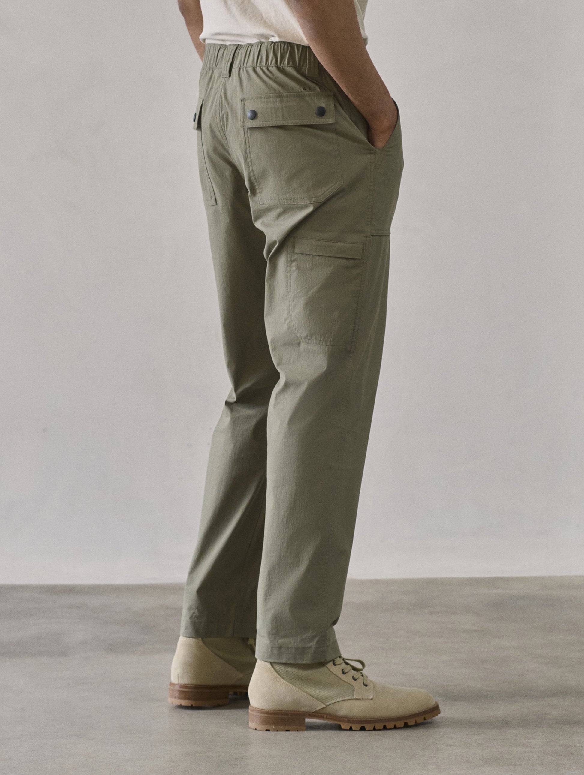Rear 3/4 lower body view of man wearing Zermatt Hiking Pant in Fern Green from AETHER Apparel.