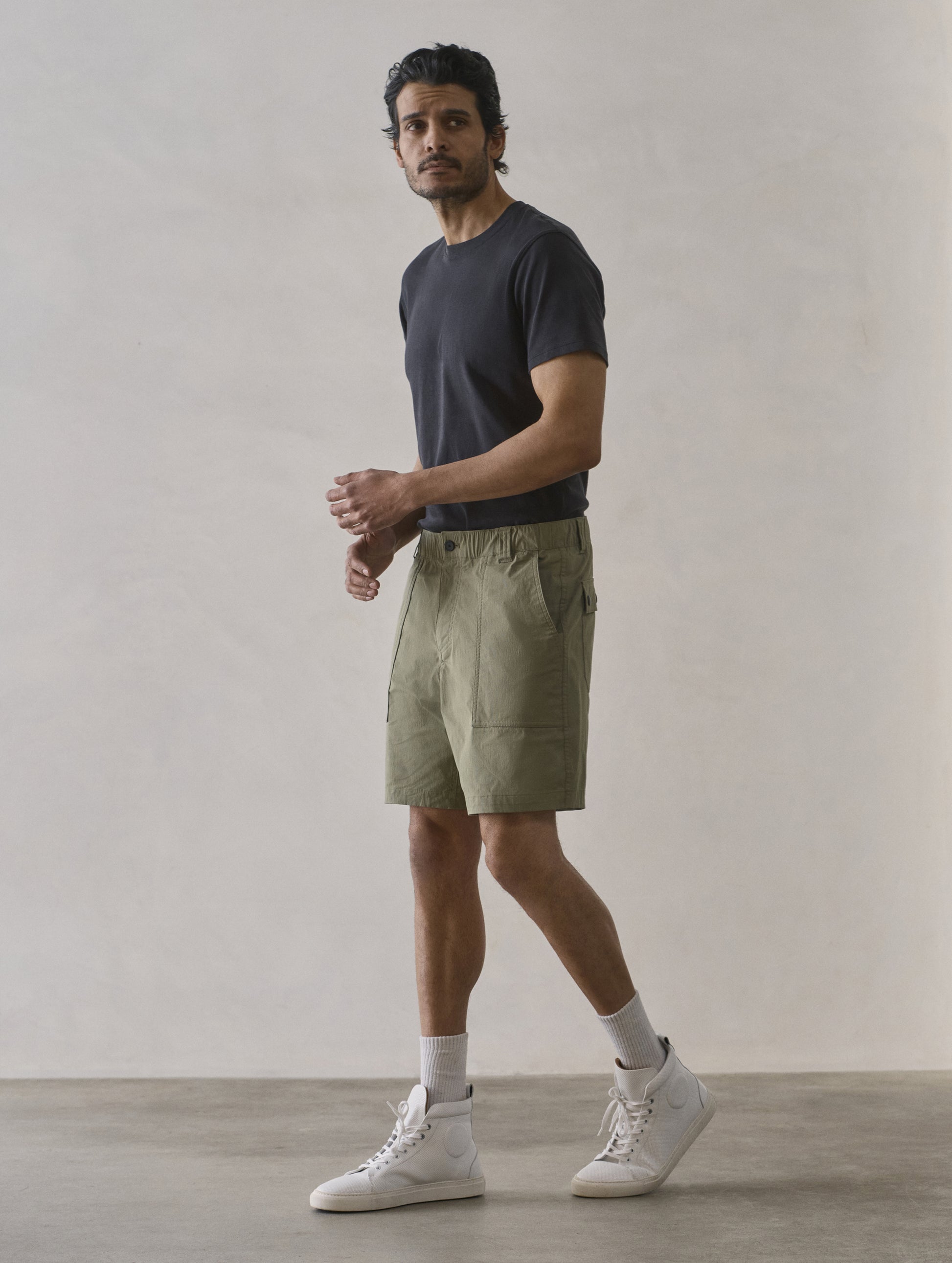 Front 3/4 full-body view of man wearing Zermatt Hiking Short in Fern Green from AETHER Apparel.