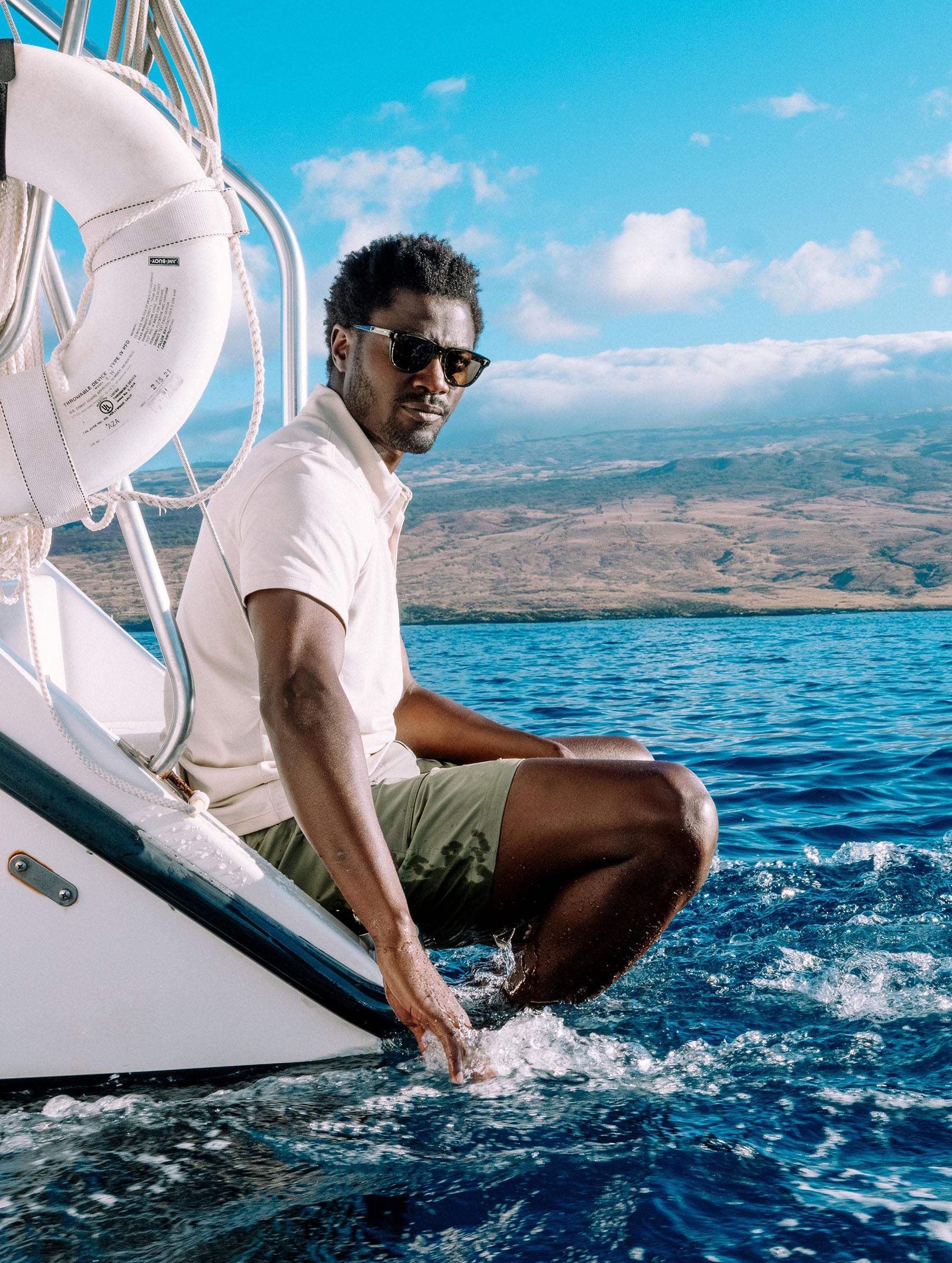 Lifestyle image of man sitting on back of boat wearing the Zermatt Hiking Short in Fern Green from AETHER Apparel.