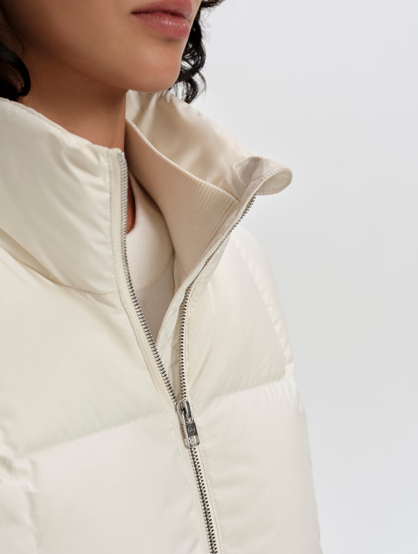 Closeup detailed view of the main center-front zipper and storm flap on the Nina Sweater Jacket 2.0 in Winter White from AETHER Apparel.