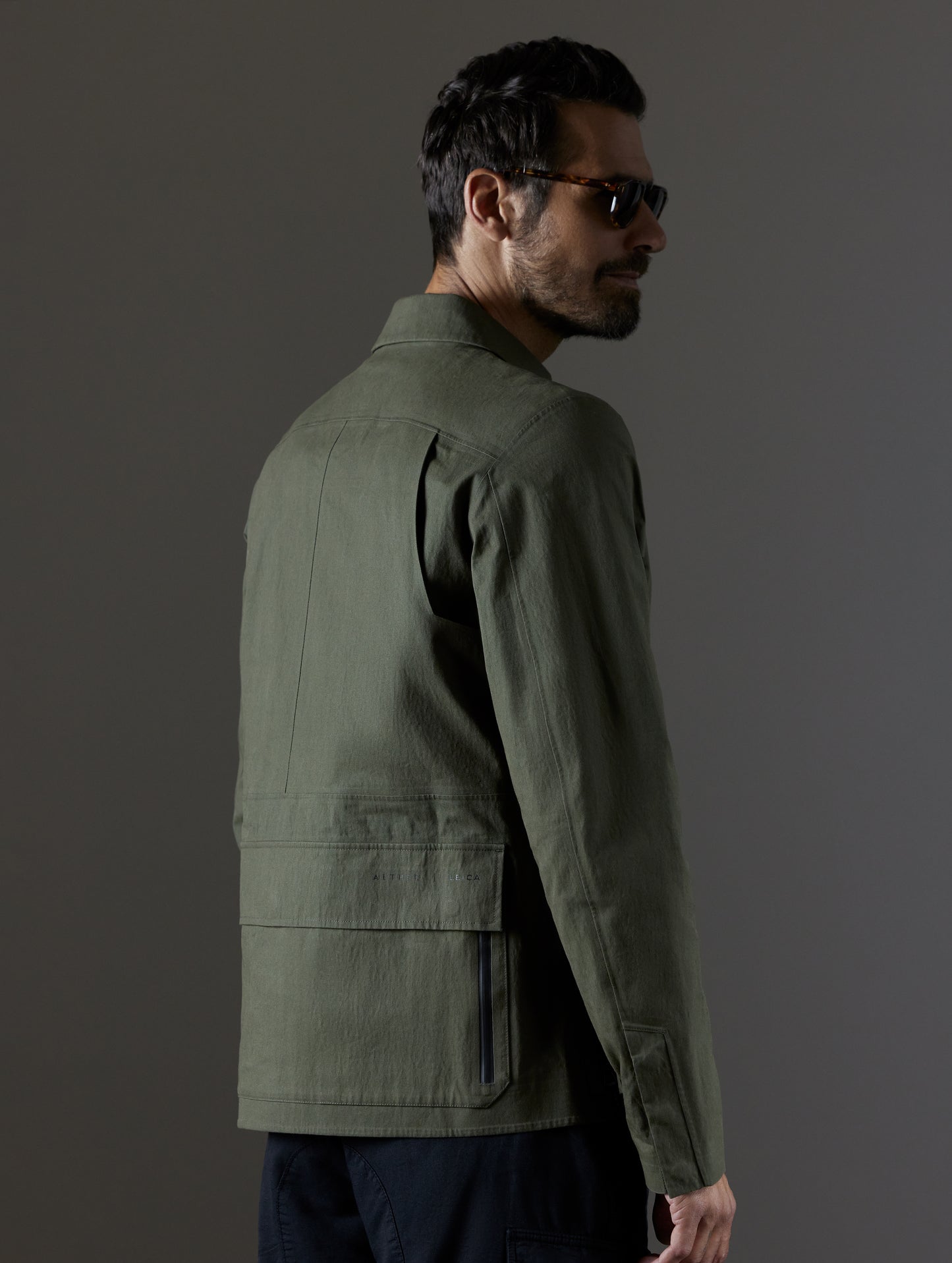 Back angled view of man wearing green Reporter Jacket from AETHER Apparel.