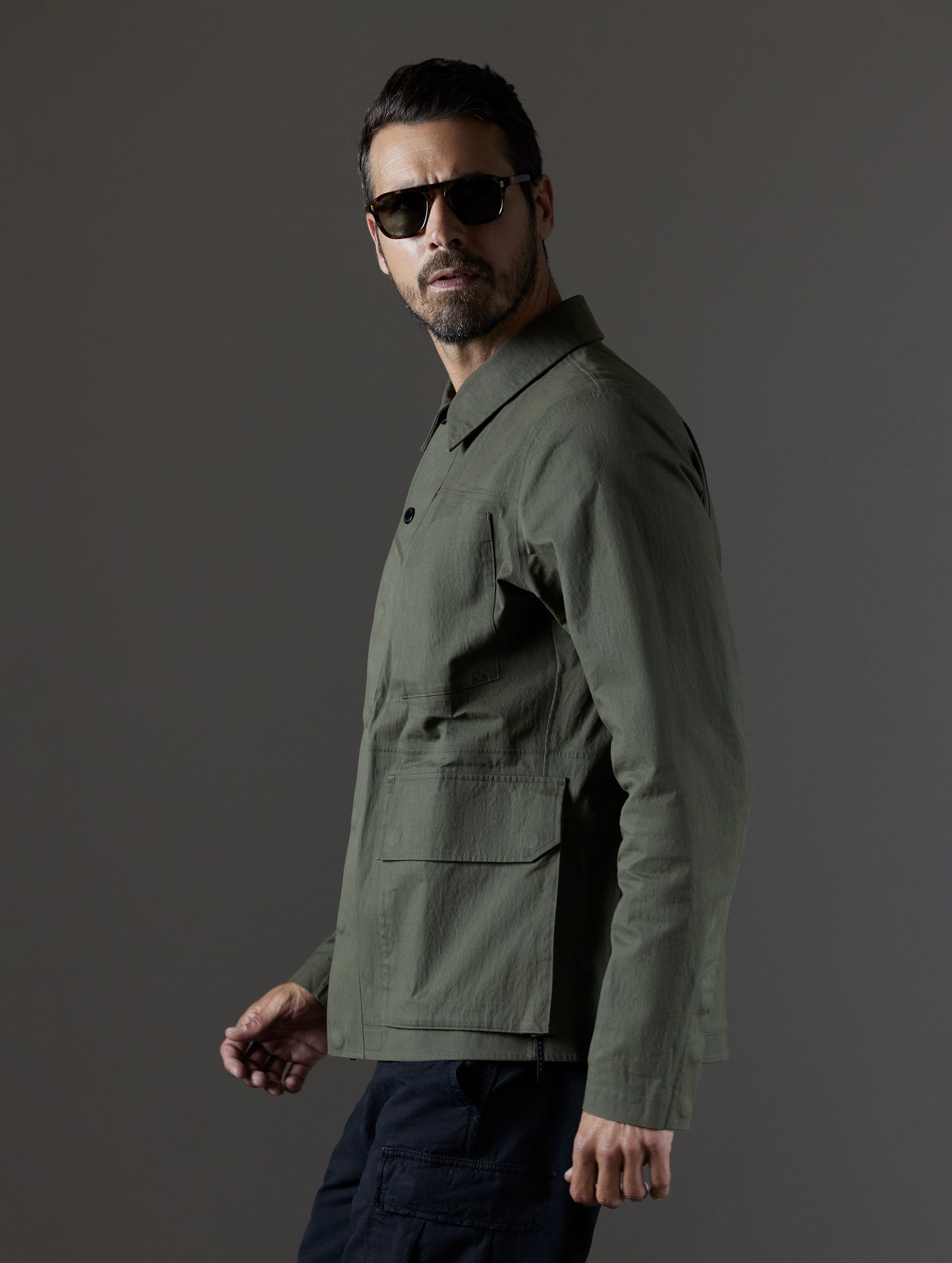 Side view of man wearing green Reporter Jacket from AETHER Apparel.