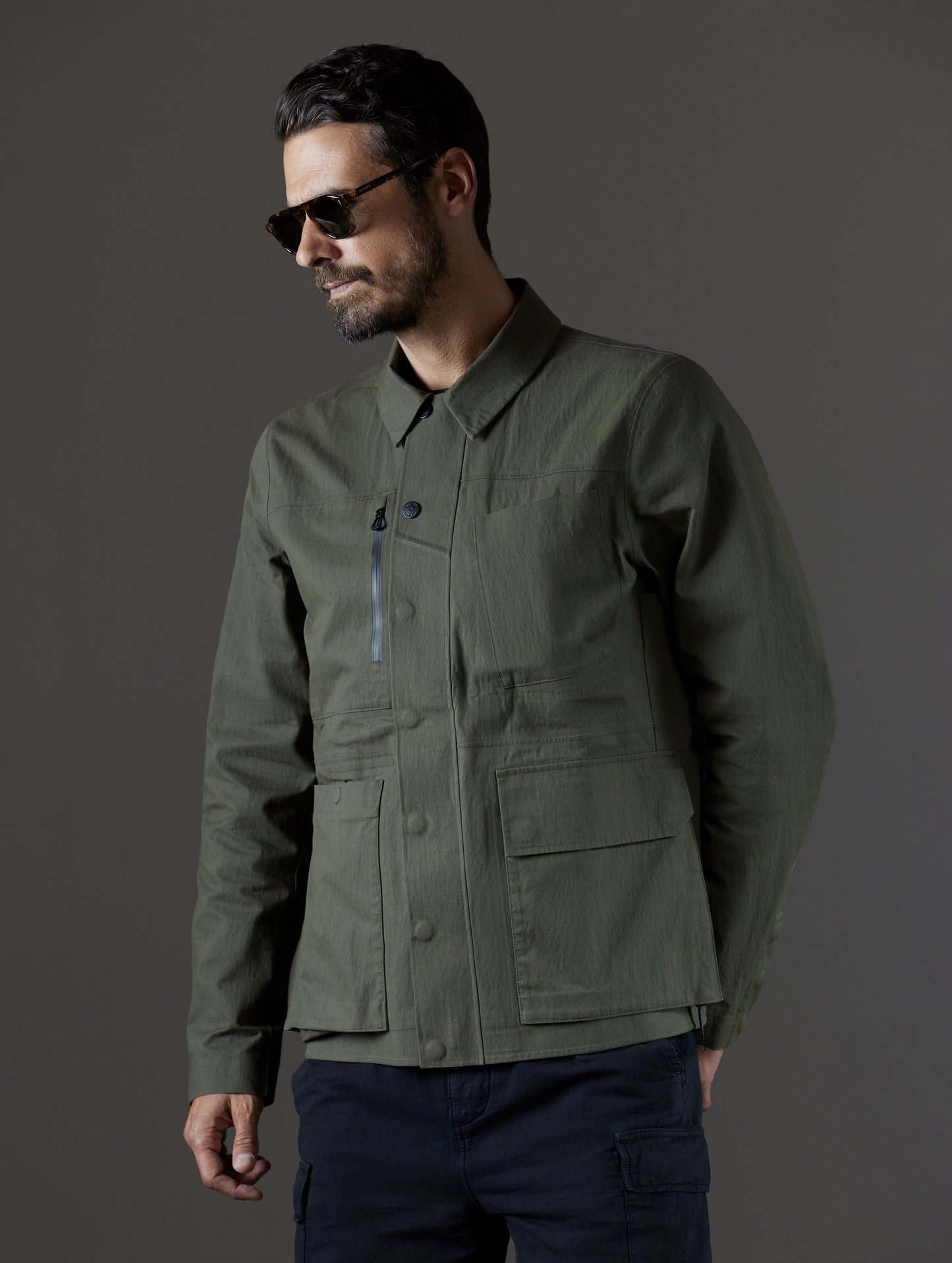 Upper body view of man wearing zipped green Reporter Jacket from AETHER Apparel.