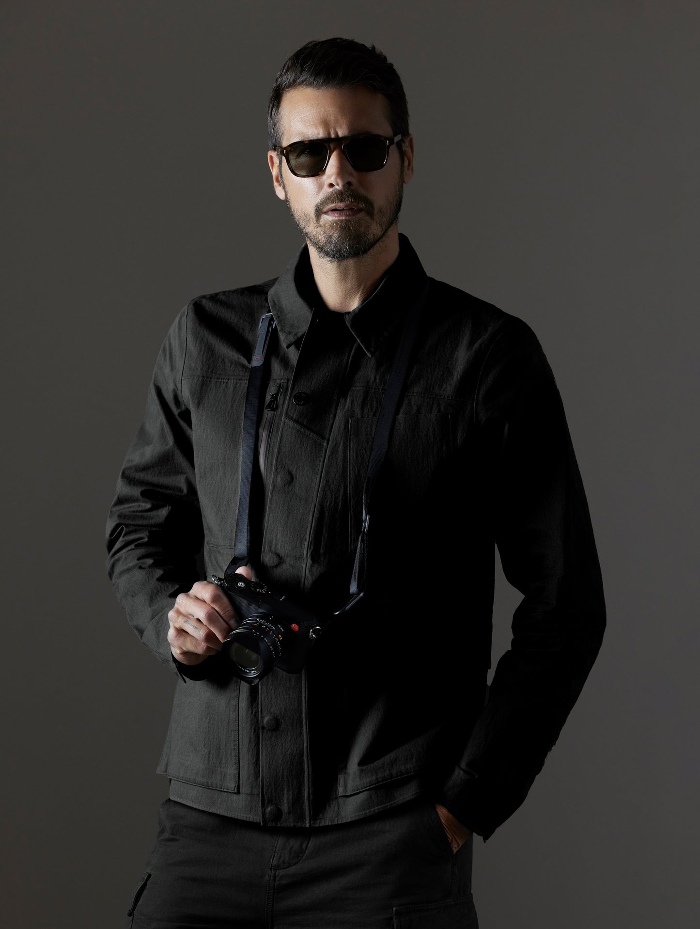 Front upper body view of man wearing buttoned-up AETHER + LEICA Reporter Jacket in Monochrom. 
