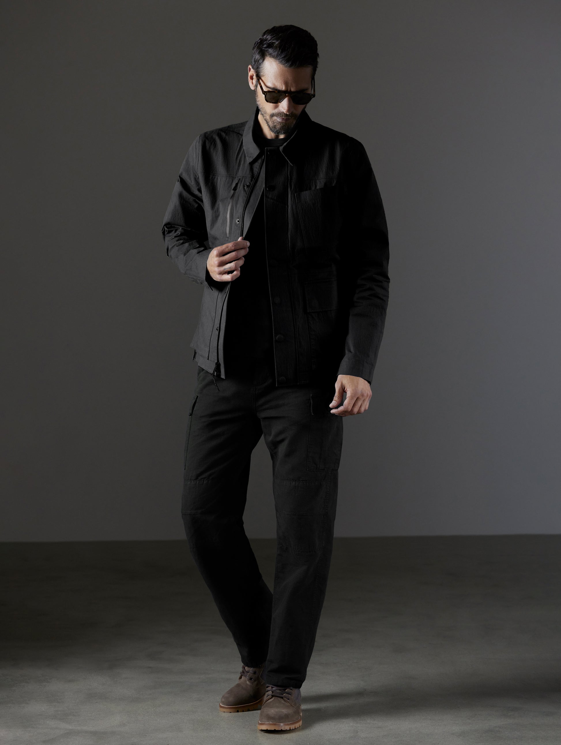 Front full body view of man wearing AETHER + LEICA Reporter Jacket in Monochrom. 