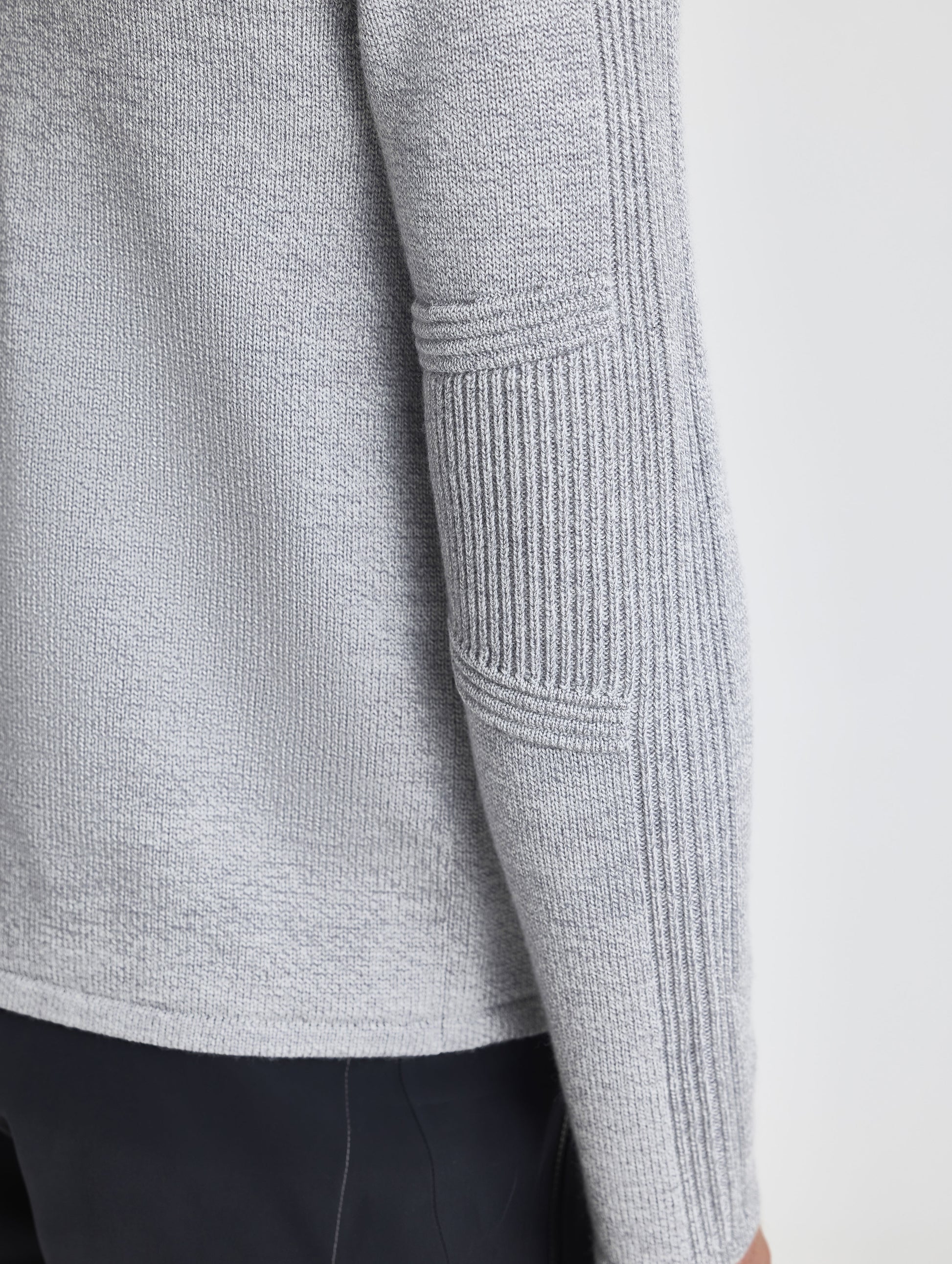 Closeup rear detail view of wearer's right sleeve patch of Riley Full-Zip Sweater in Light Heather Grey from AETHER Apparel.