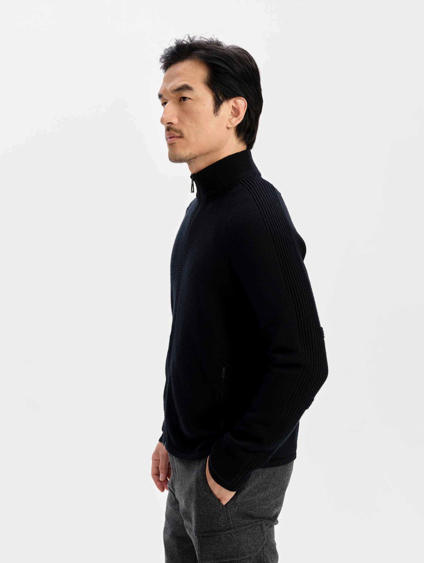 Side profile upper-body view of man wearing the Riley Full-Zip Sweater in Onyx Black from AETHER Apparel. 