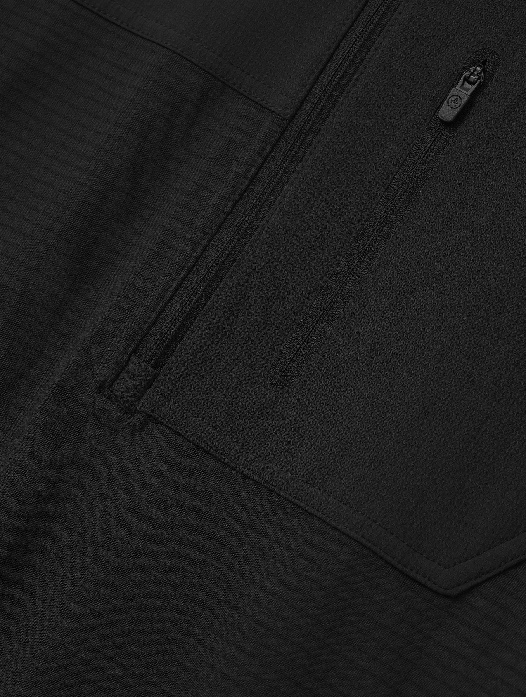 Closeup detailed view of the offset, zipper-secured chest pocket on the Rocklin Half-Zip in Onyx Black from AETHER Apparel.