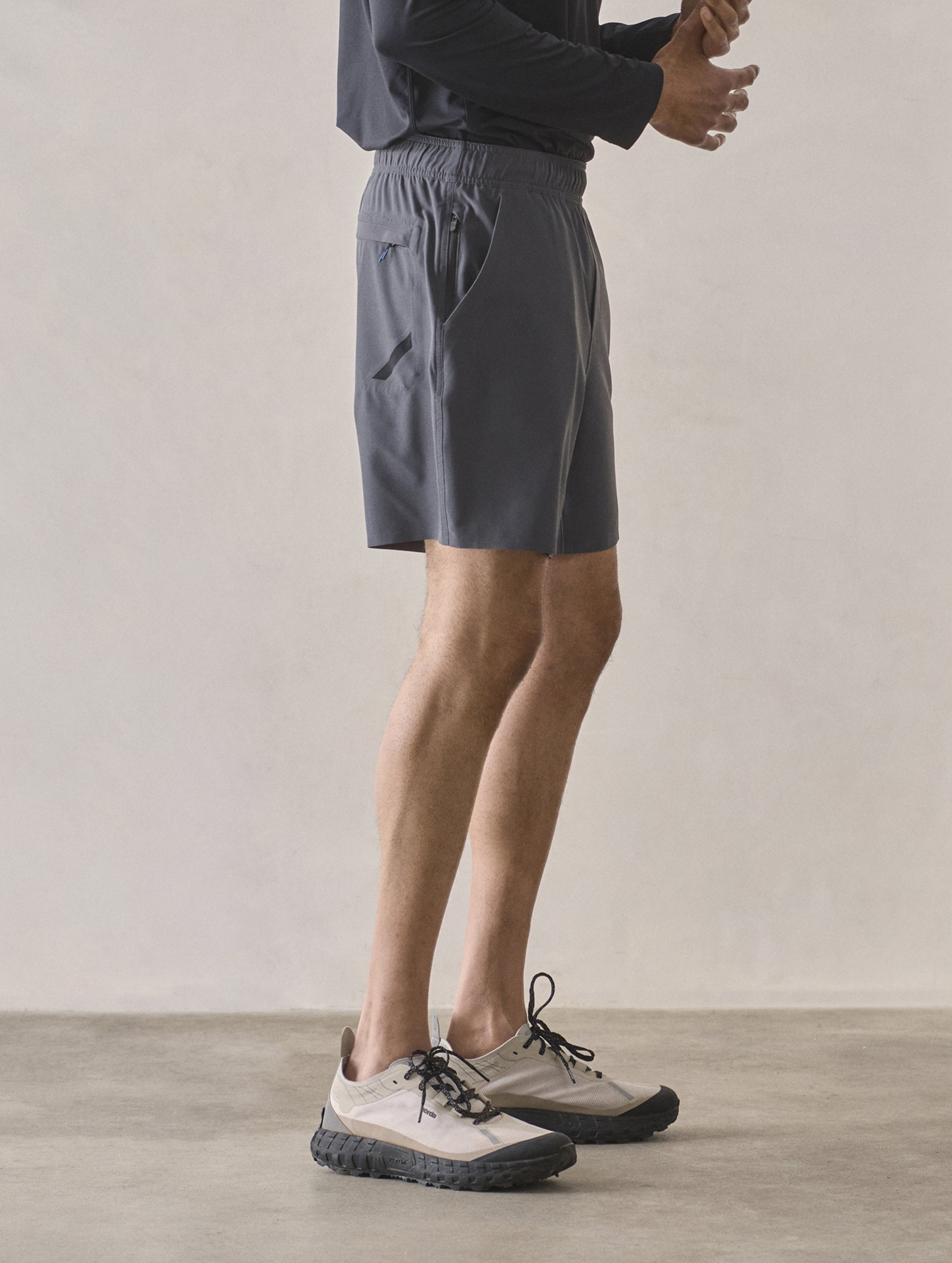 Right side profile lower-body view of man wearing Rogue Hybrid Short in Graphite from AETHER Apparel.