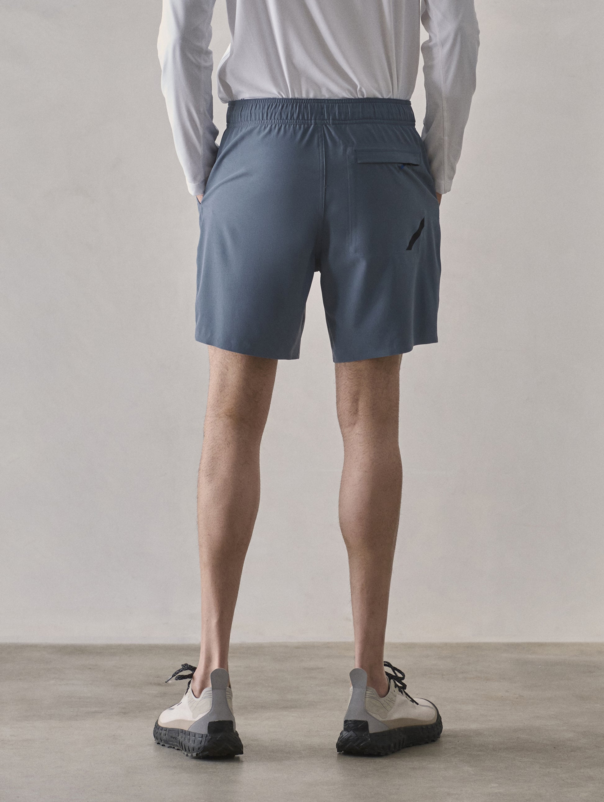 Rear lower-body view of man wearing Rogue Hybrid Short in Portal Blue from AETHER Apparel.
