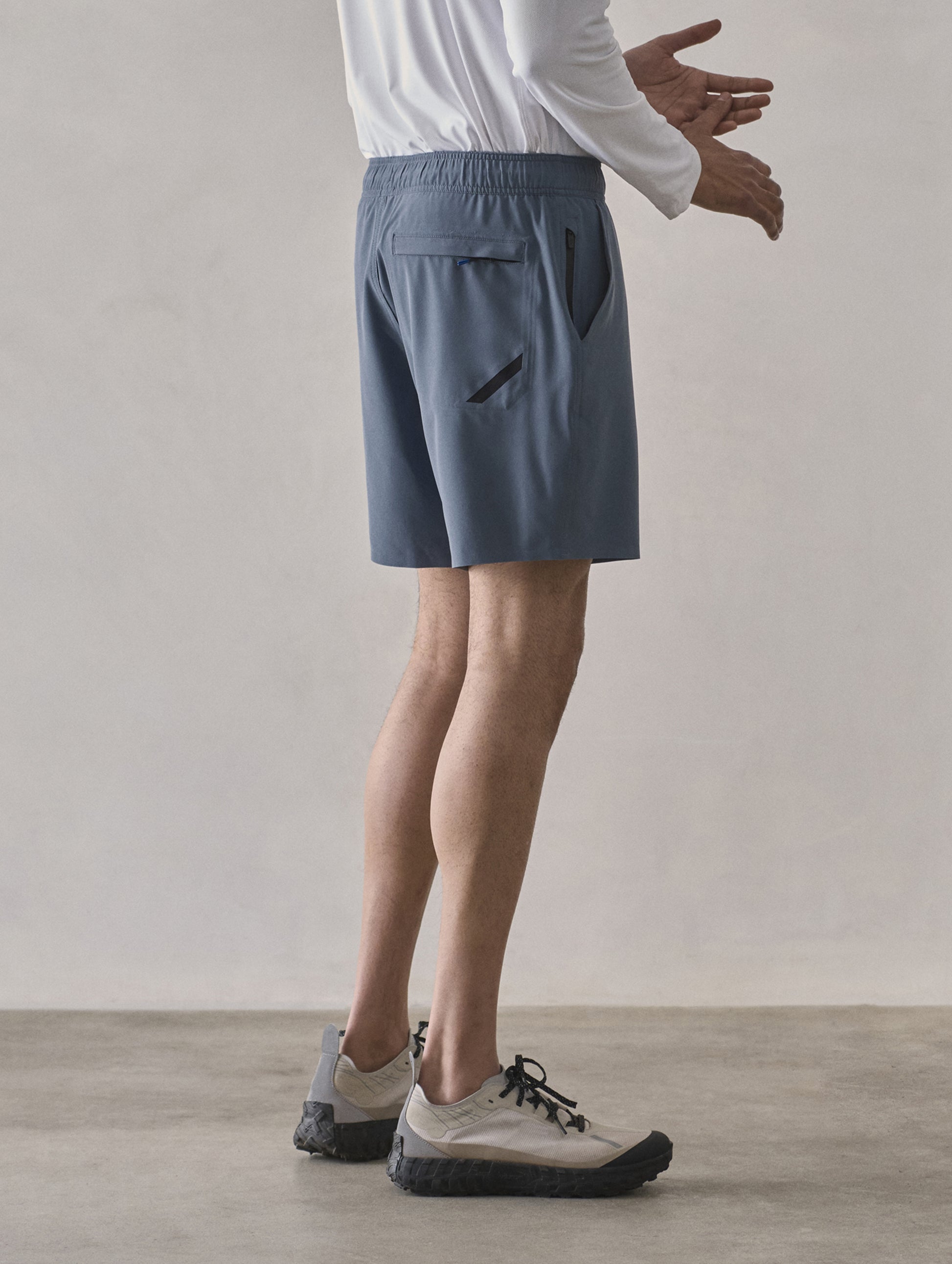 Side profile lower-body view of man wearing Rogue Hybrid Short in Portal Blue from AETHER Apparel.