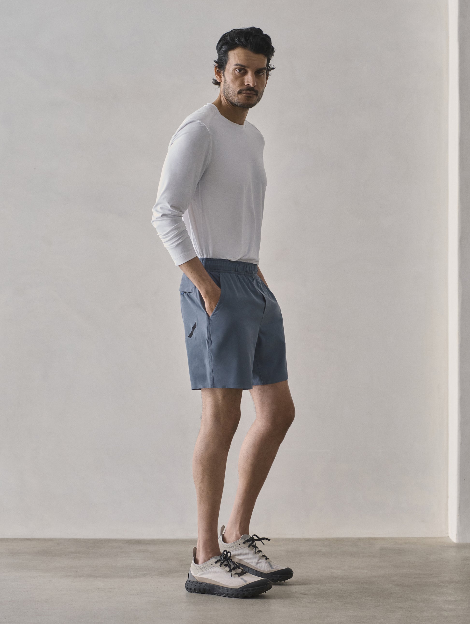 Front 3/4 full-body view of man wearing Rogue Hybrid Short in Portal Blue from AETHER Apparel.