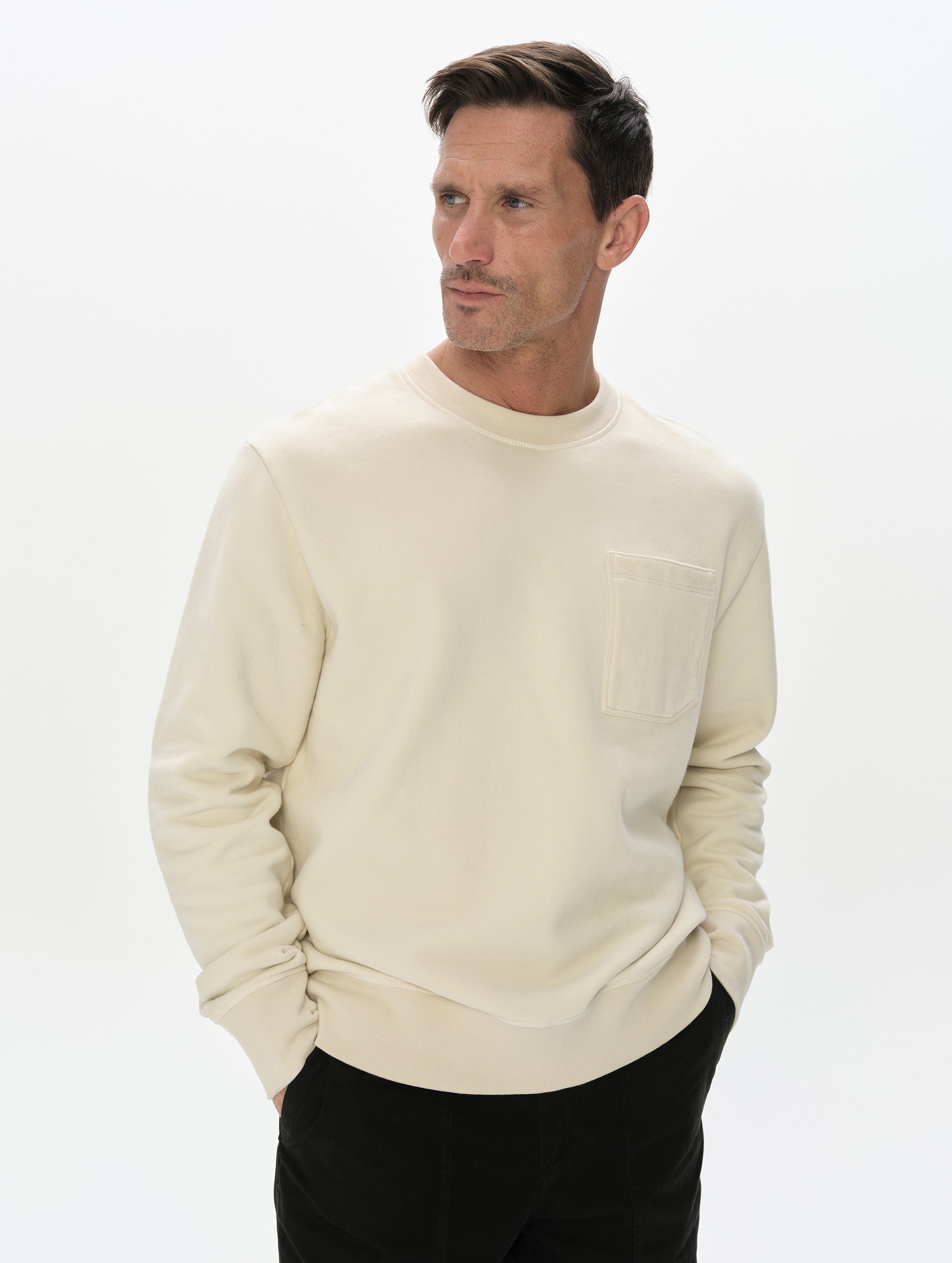 Front, upper-body view of man wearing the Rylan Crewneck Sweatshirt in Bone from AETHER Apparel.