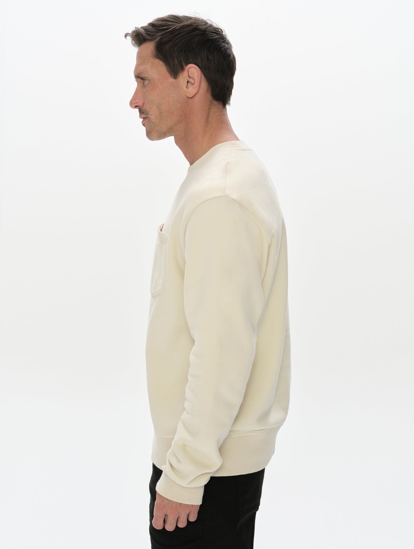Side profile, upper-body view of man wearing the Rylan Crewneck Sweatshirt in Bone from AETHER Apparel.