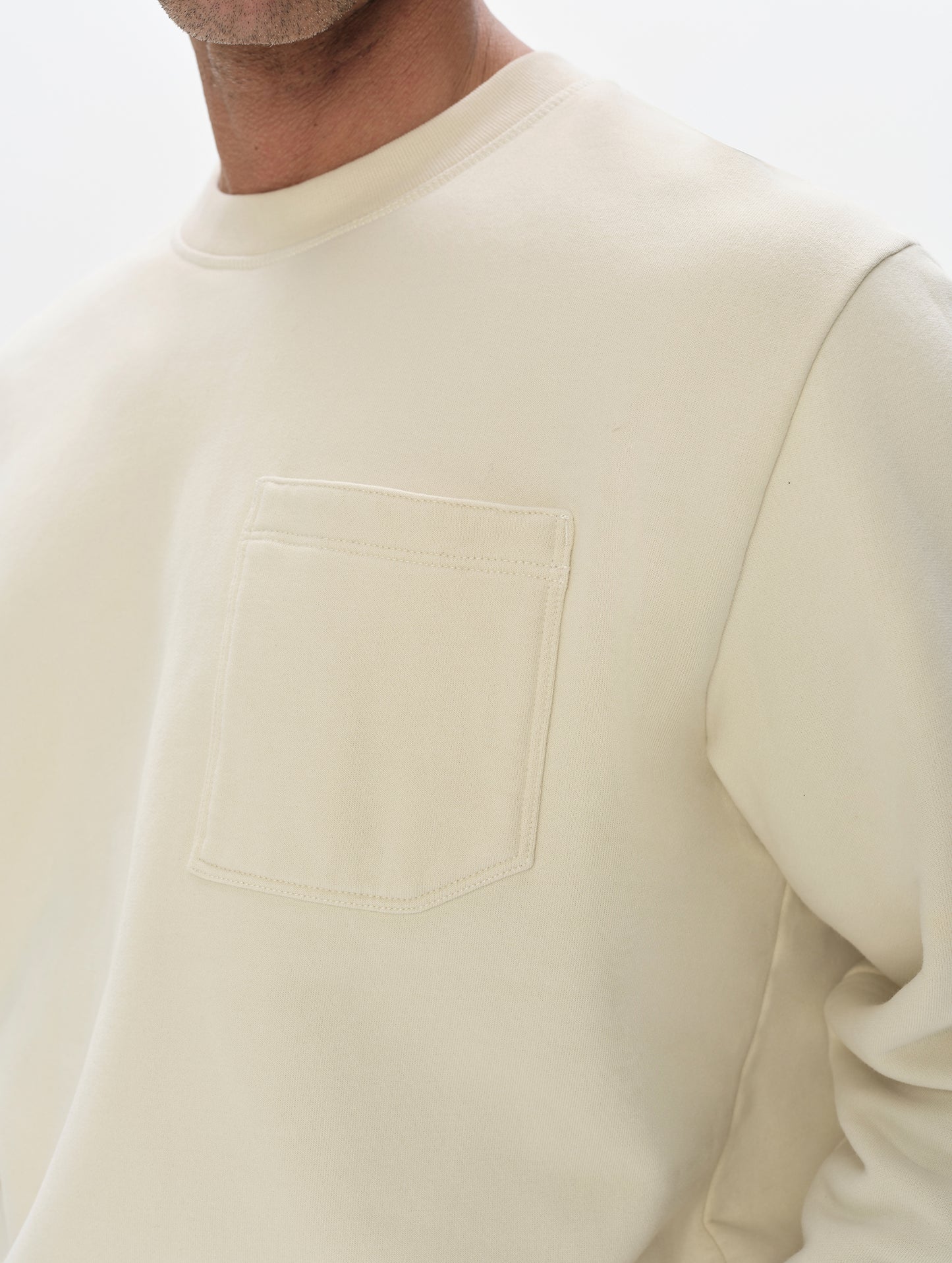 Closeup detailed view of the shoulder and patch pocket on the Rylan Crewneck Sweatshirt in Bone from AETHER Apparel.