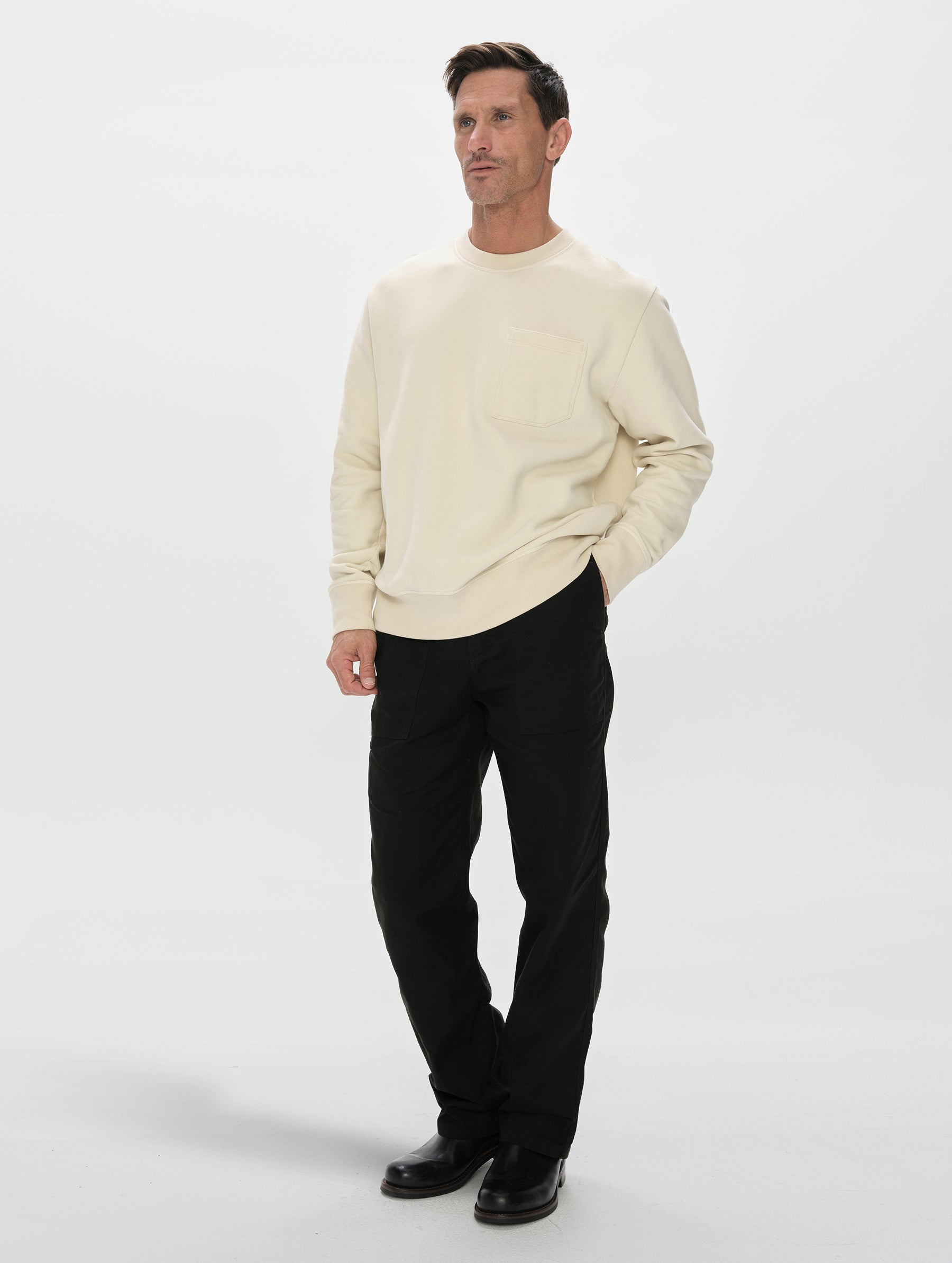 Front, 3/4, full-body view of man wearing the Rylan Crewneck Sweatshirt in Bone from AETHER Apparel.
