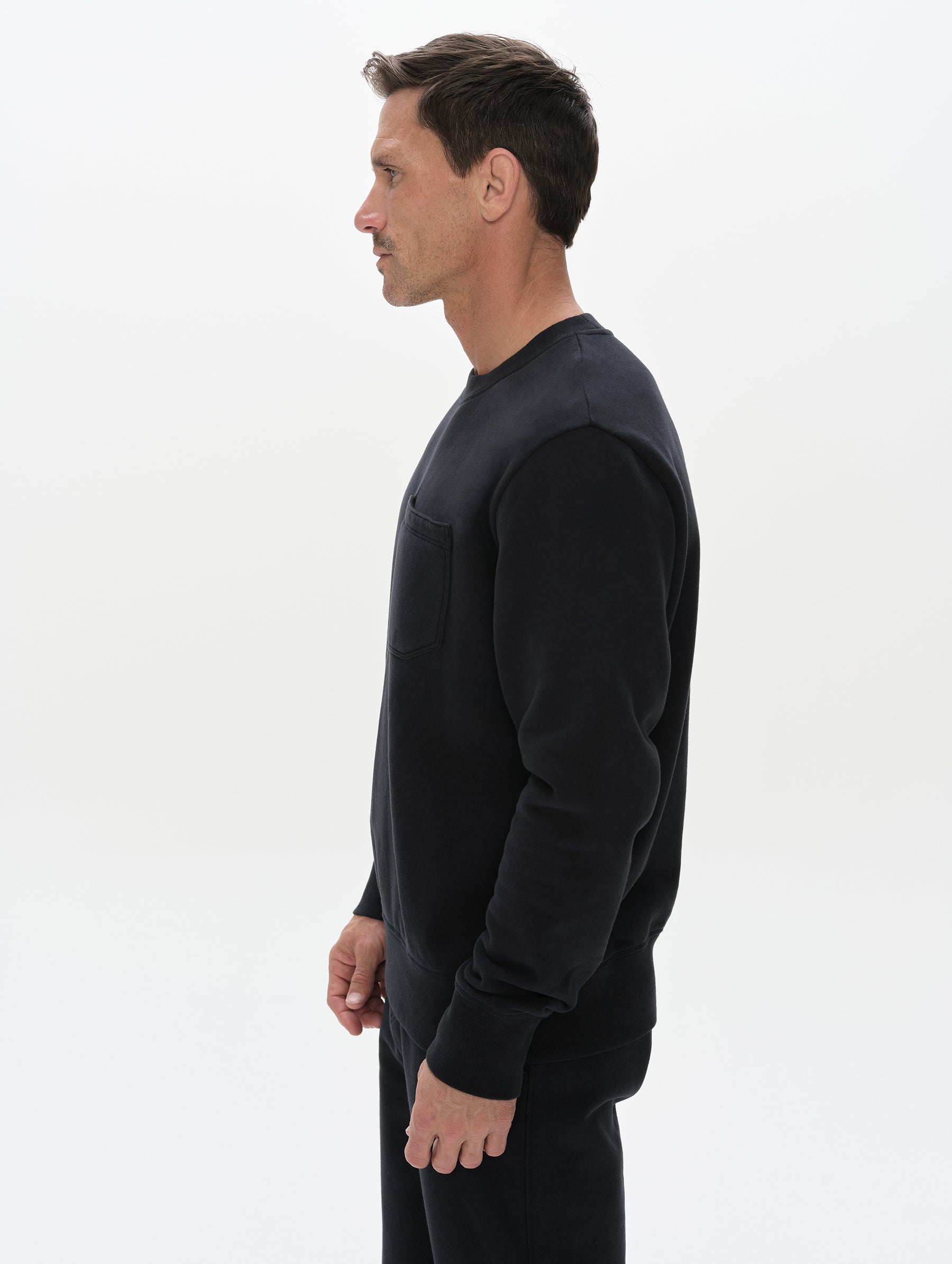 Side profile, upper-body view of man wearing the Rylan Crewneck Sweatshirt in Onyx Black from AETHER Apparel.