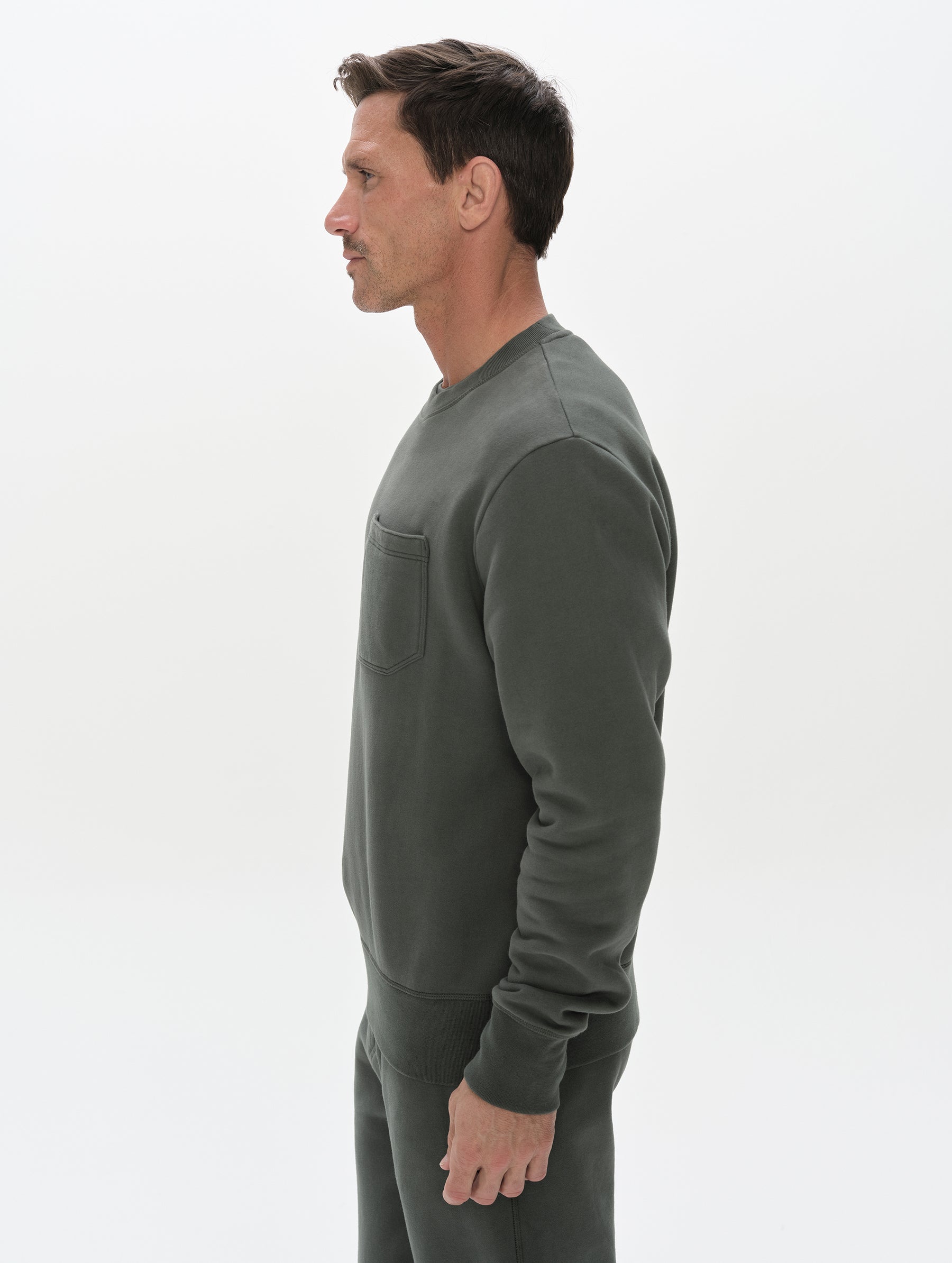 Side profile, upper-body view of man wearing the Rylan Crewneck Sweatshirt in Saville Green from AETHER Apparel.