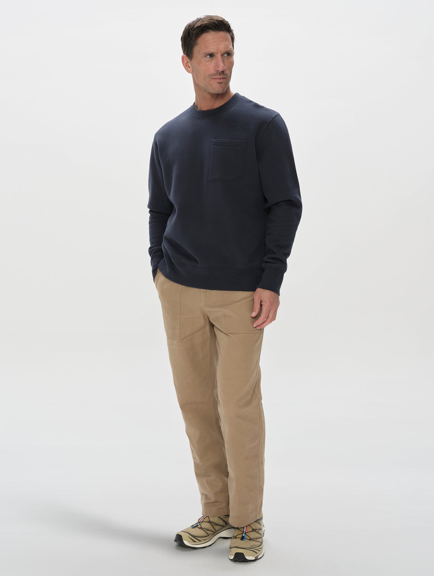 Front, 3/4, full-body view of man wearing the Rylan Crewneck Sweatshirt in Total Eclipse from AETHER Apparel.