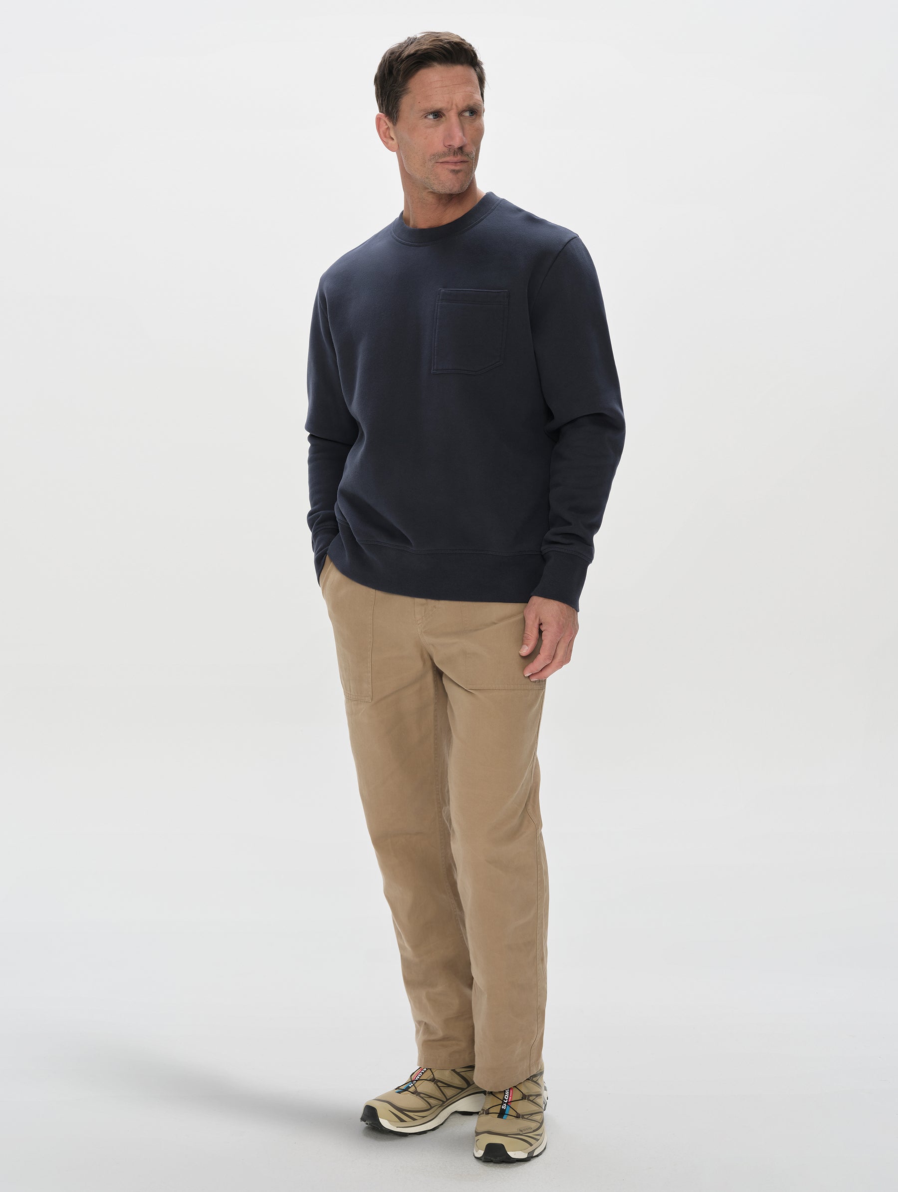 Front, 3/4, full-body view of man wearing the Rylan Crewneck Sweatshirt in Total Eclipse from AETHER Apparel.