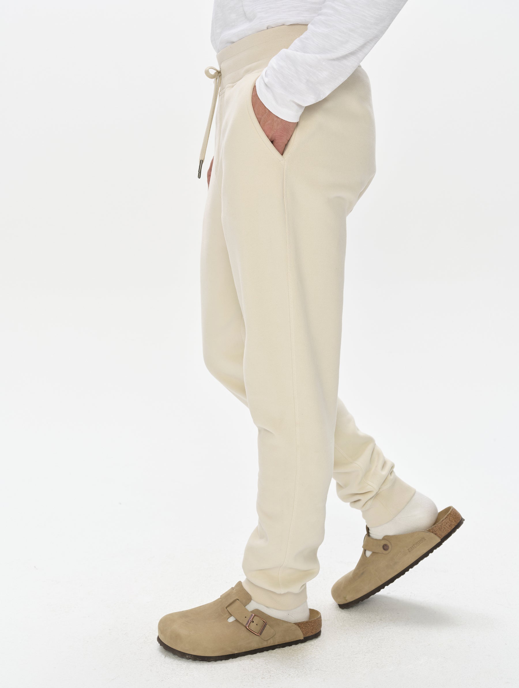 Side profile, lower-body view of man wearing the Rylan Cuffed Sweatpant in Bone from AETHER Apparel.