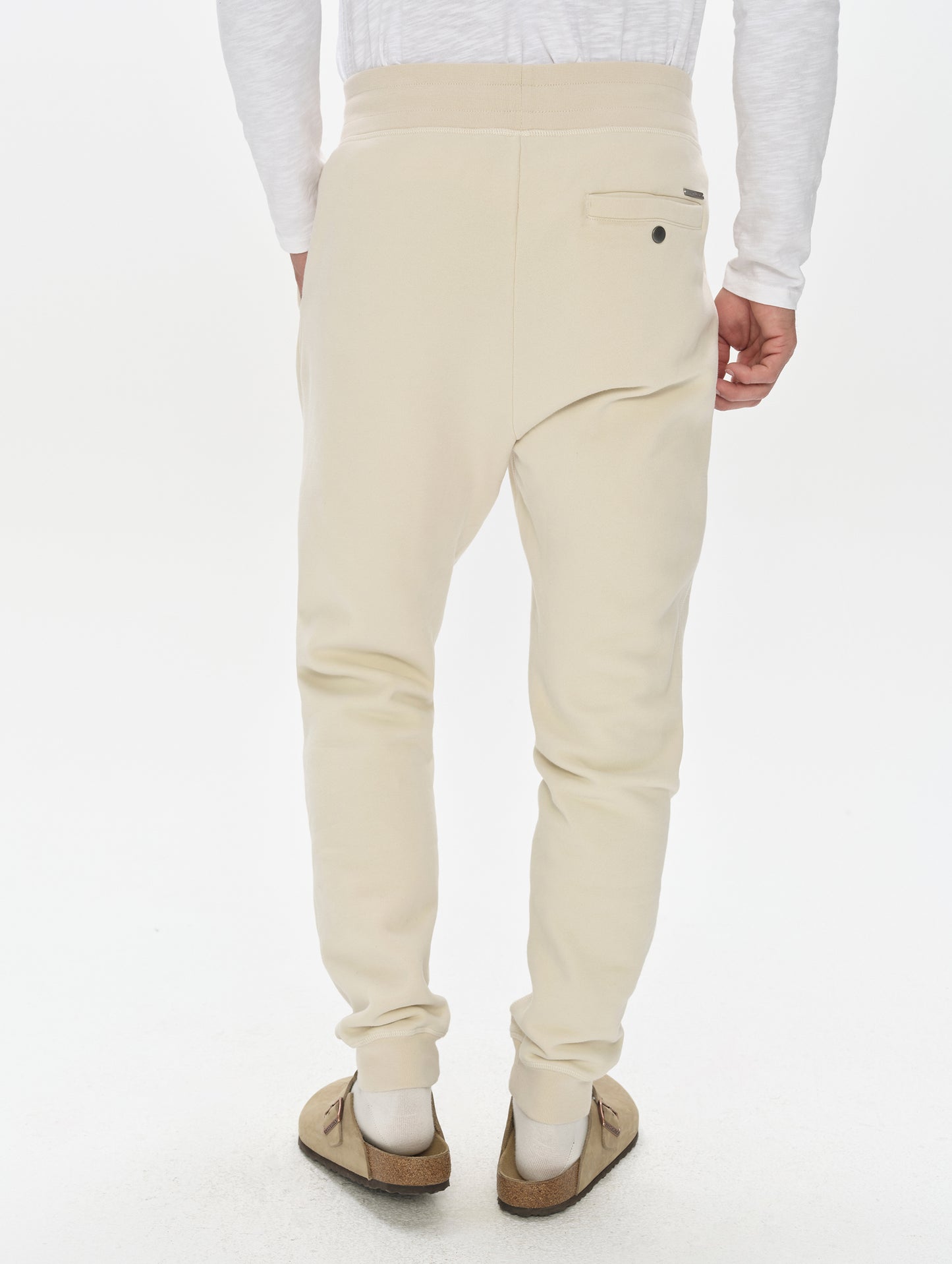 Rear, lower-body view of man wearing the Rylan Cuffed Sweatpant in Bone from AETHER Apparel.