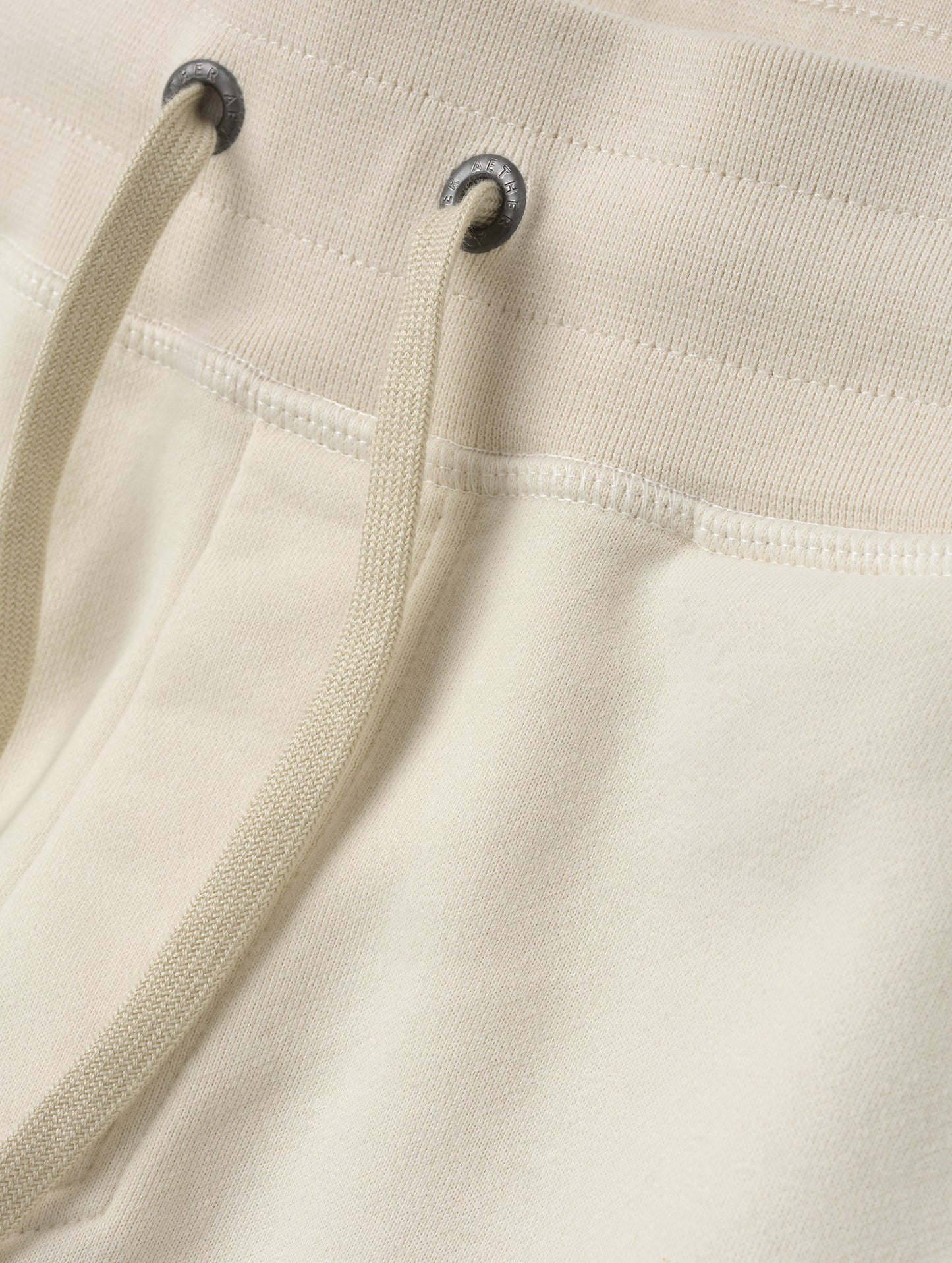 Closeup detailed view of the drawstring closure on the Rylan Cuffed Sweatpant in Bone from AETHER Apparel.