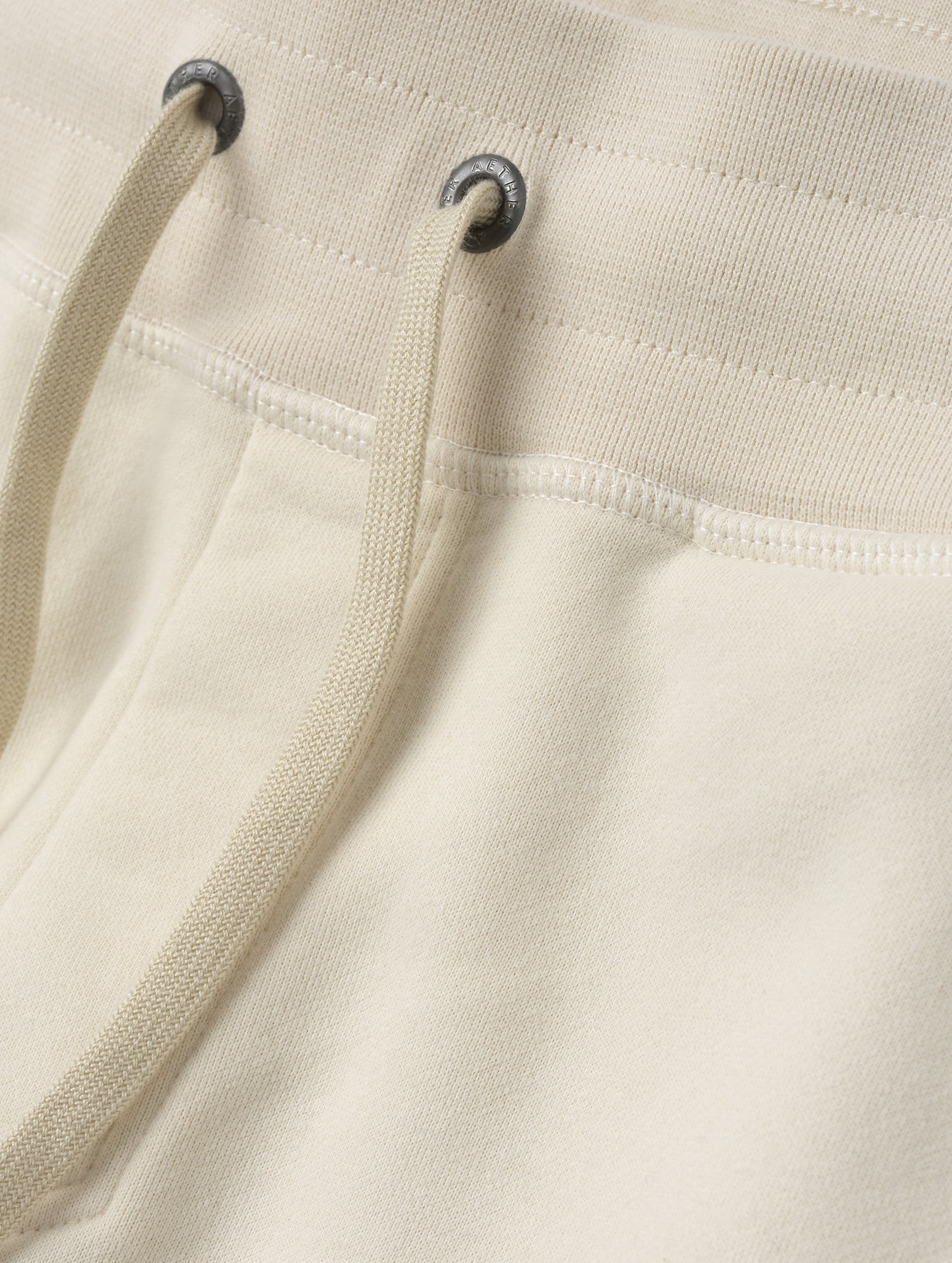 Closeup detailed view of the drawstring closure on the Rylan Cuffed Sweatpant in Bone from AETHER Apparel.