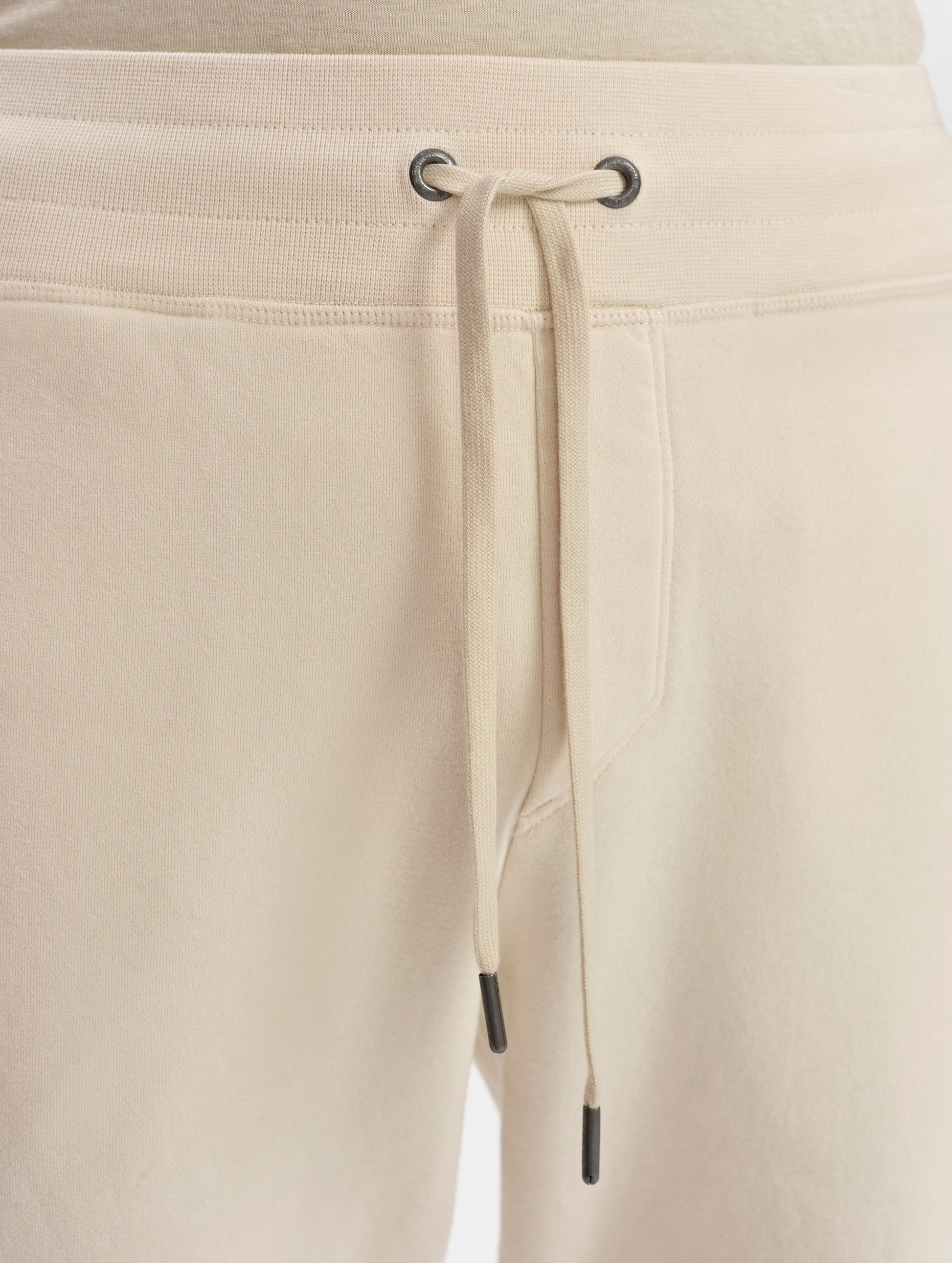 Closeup detailed view of the metal-tipped drawstring closure on the Rylan Sweat Pant in Bone from AETHER Apparel. 