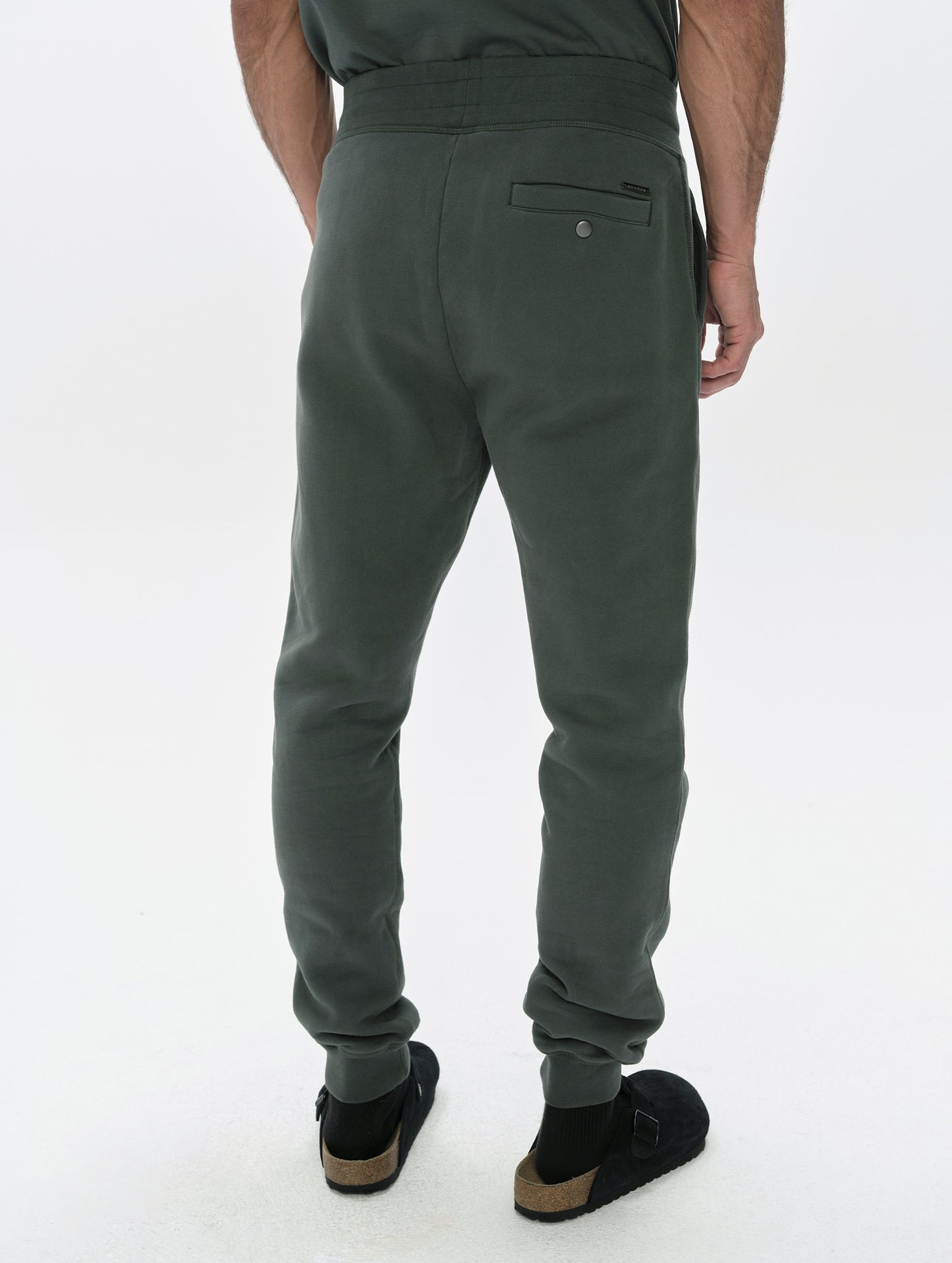 Rear, lower-body view of man wearing the Rylan Cuffed Sweatpant in Saville Green  from AETHER Apparel.