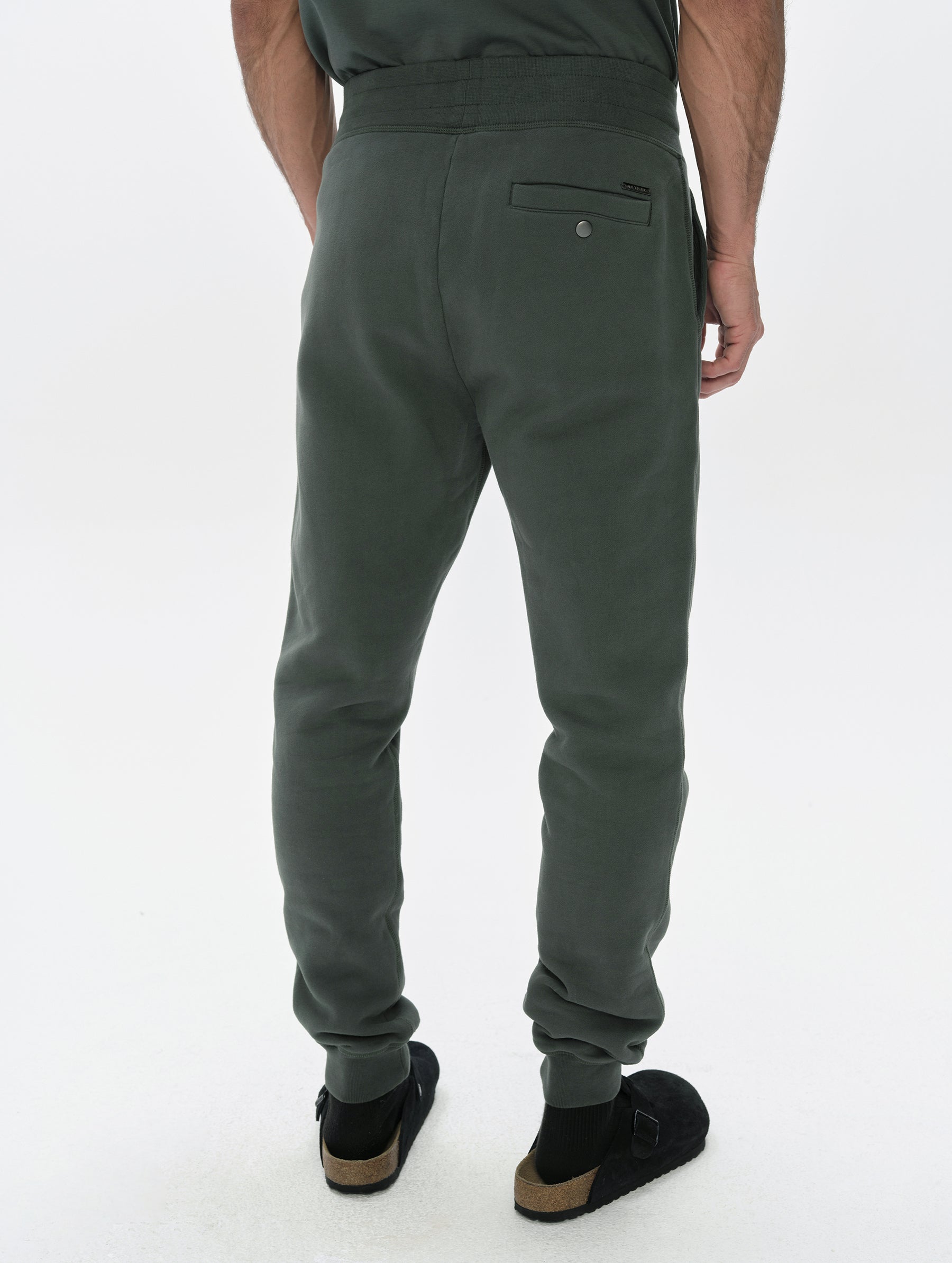 Rear, lower-body view of man wearing the Rylan Cuffed Sweatpant in Saville Green  from AETHER Apparel.