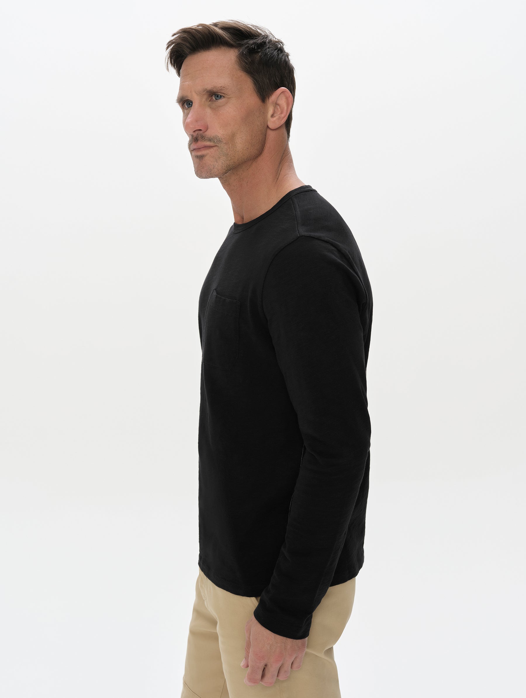 Side profile, upper-body view of man wearing the Slub Pocket Long-Sleeve Tee 2.0 in Onyx Black from AETHER Apparel.