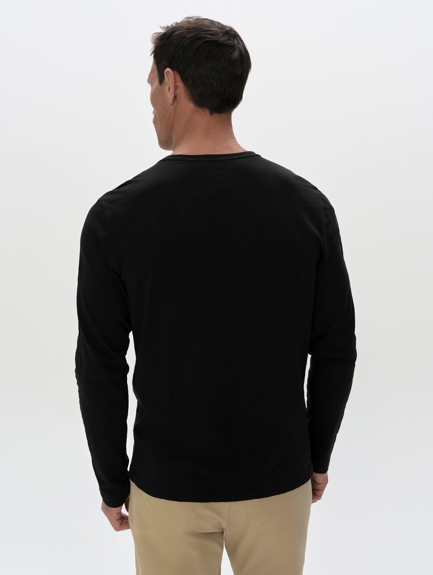 Rear, upper-body view of man wearing the Slub Pocket Long-Sleeve Tee 2.0 in Onyx Black from AETHER Apparel.