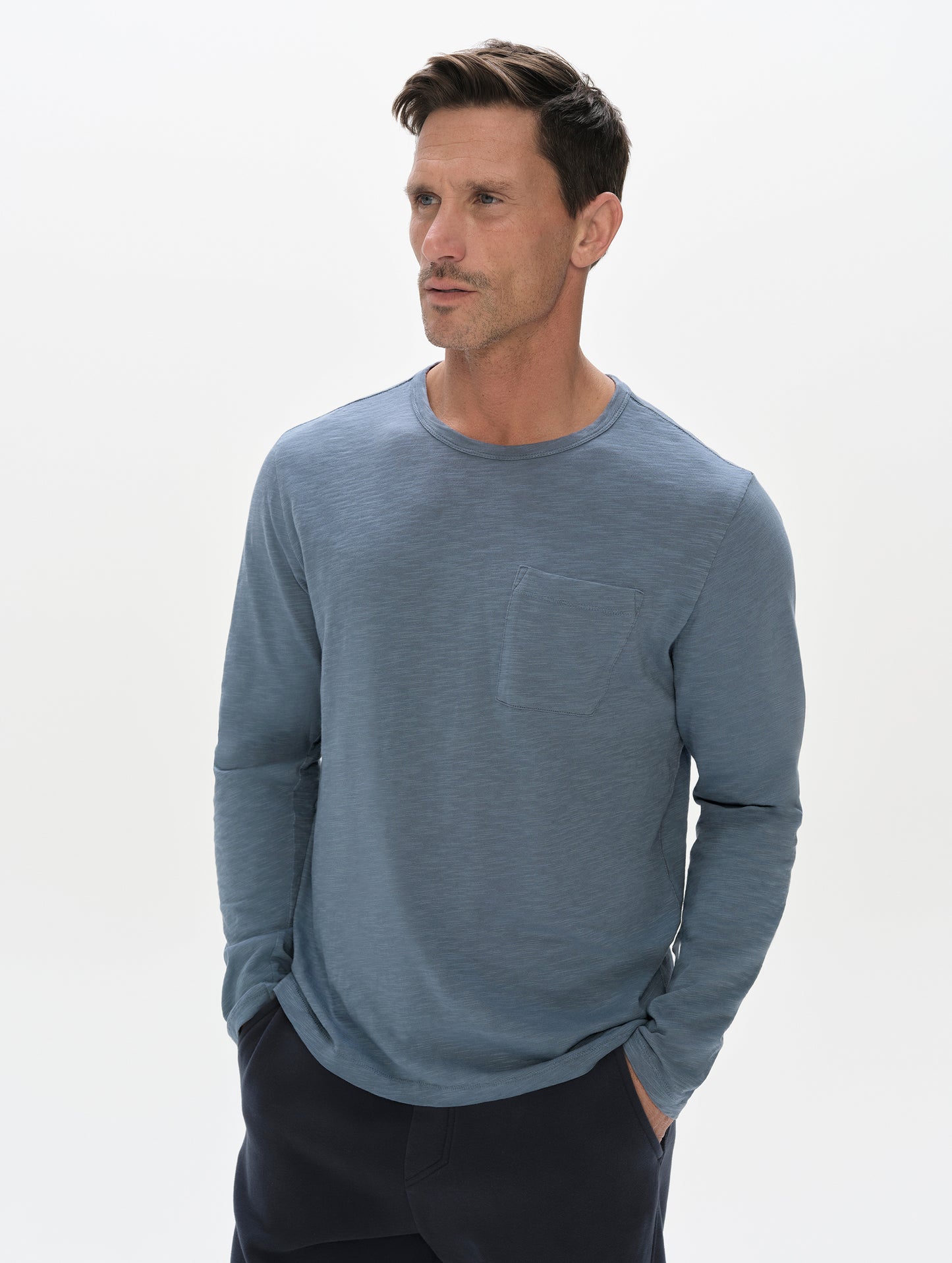 Front, upper-body view of man wearing the Slub Pocket Long-Sleeve Tee 2.0 in Portal Blue from AETHER Apparel.