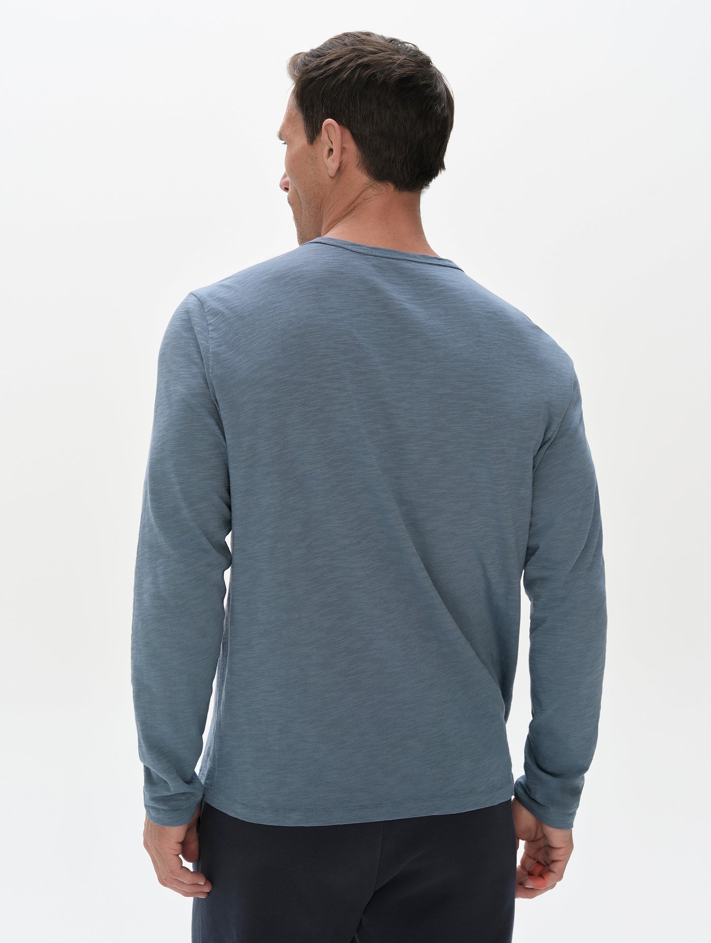 Rear, upper-body view of man wearing the Slub Pocket Long-Sleeve Tee 2.0 in Portal Blue from AETHER Apparel.
