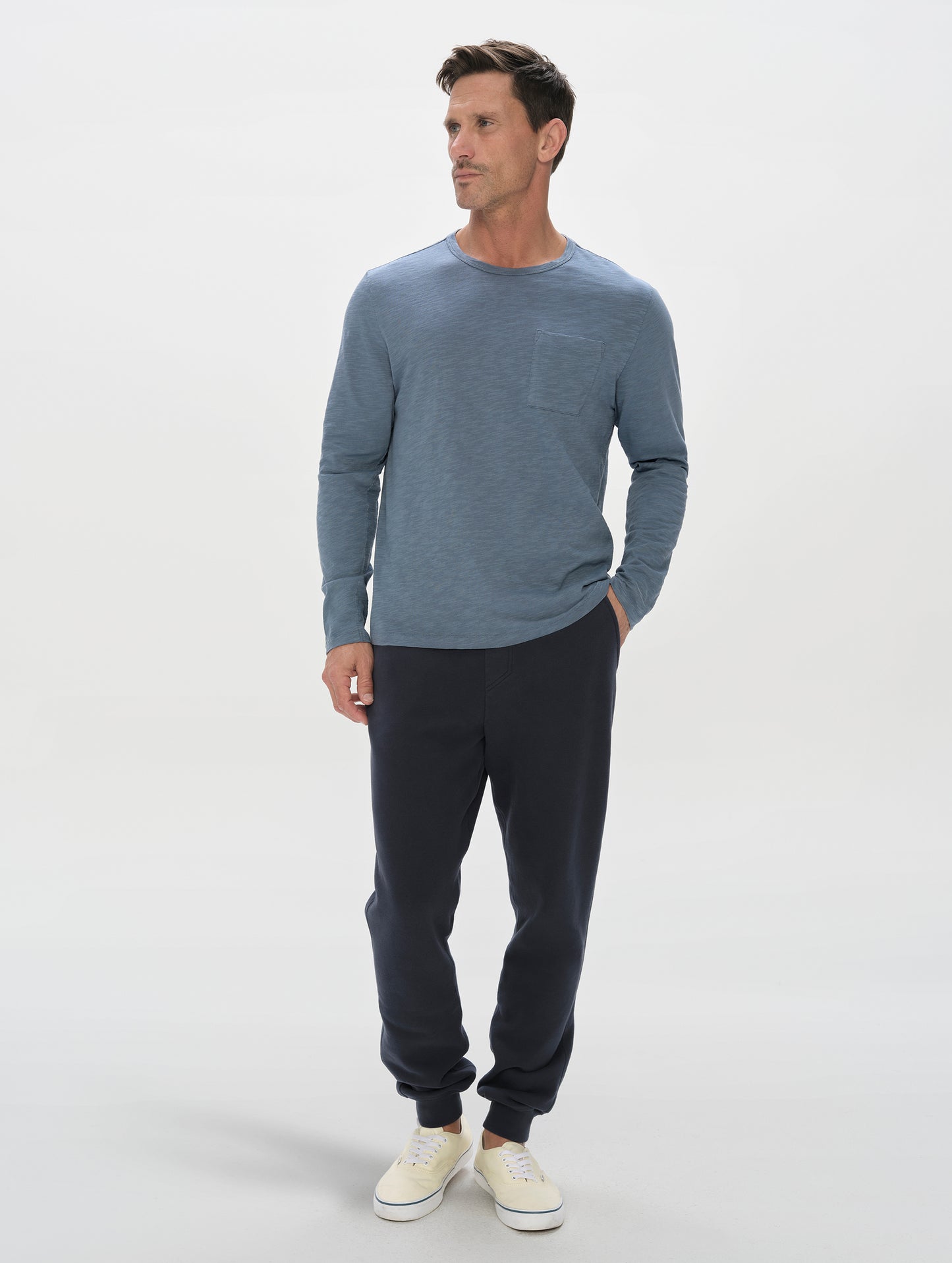 Front, full-body view of man wearing the Slub Pocket Long-Sleeve Tee 2.0 in Portal Blue from AETHER Apparel.