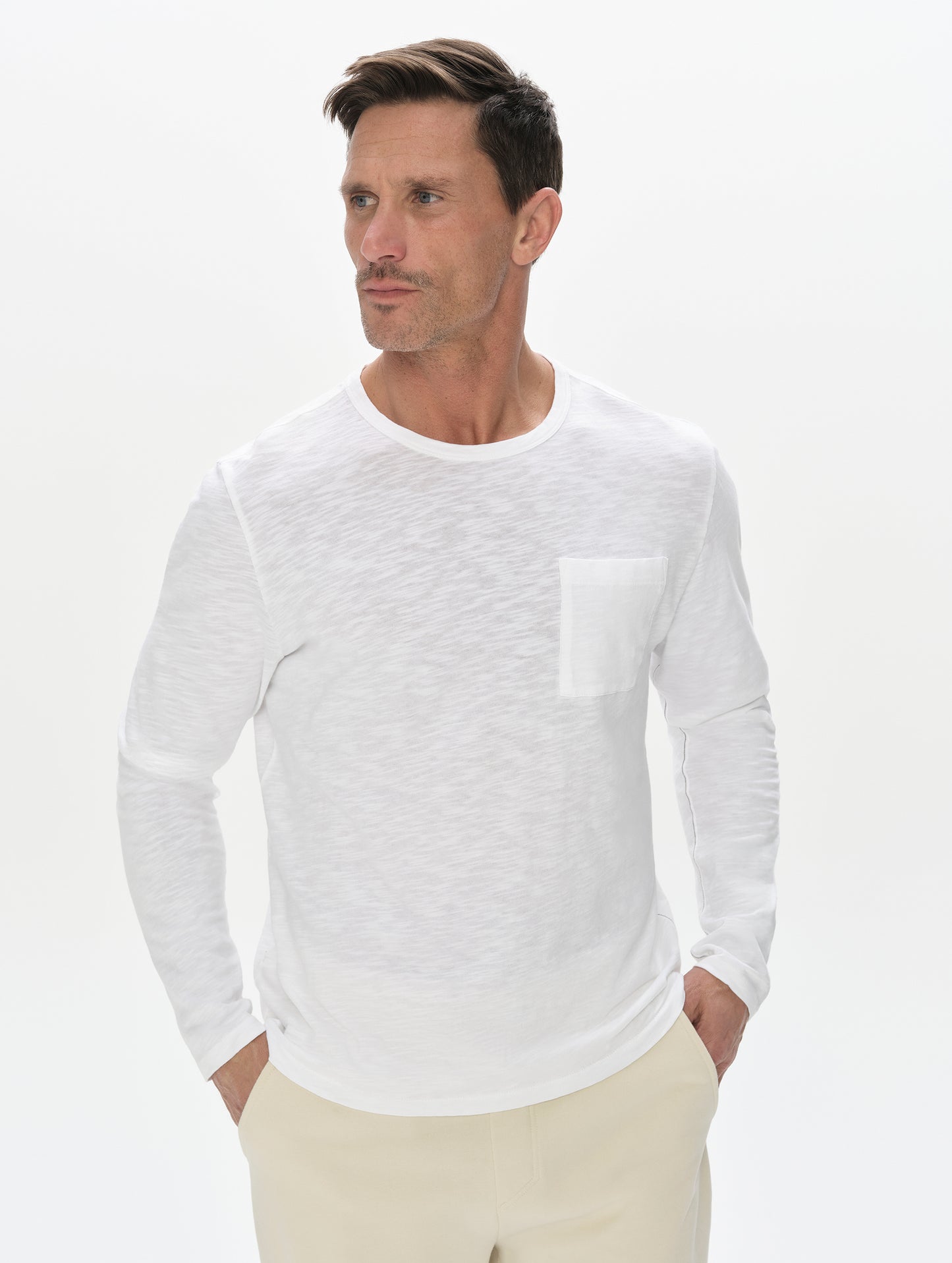 Front, upper-body view of man wearing Slub Long-Sleeve Pocket Tee 2.0 in White from AETHER Apparel.