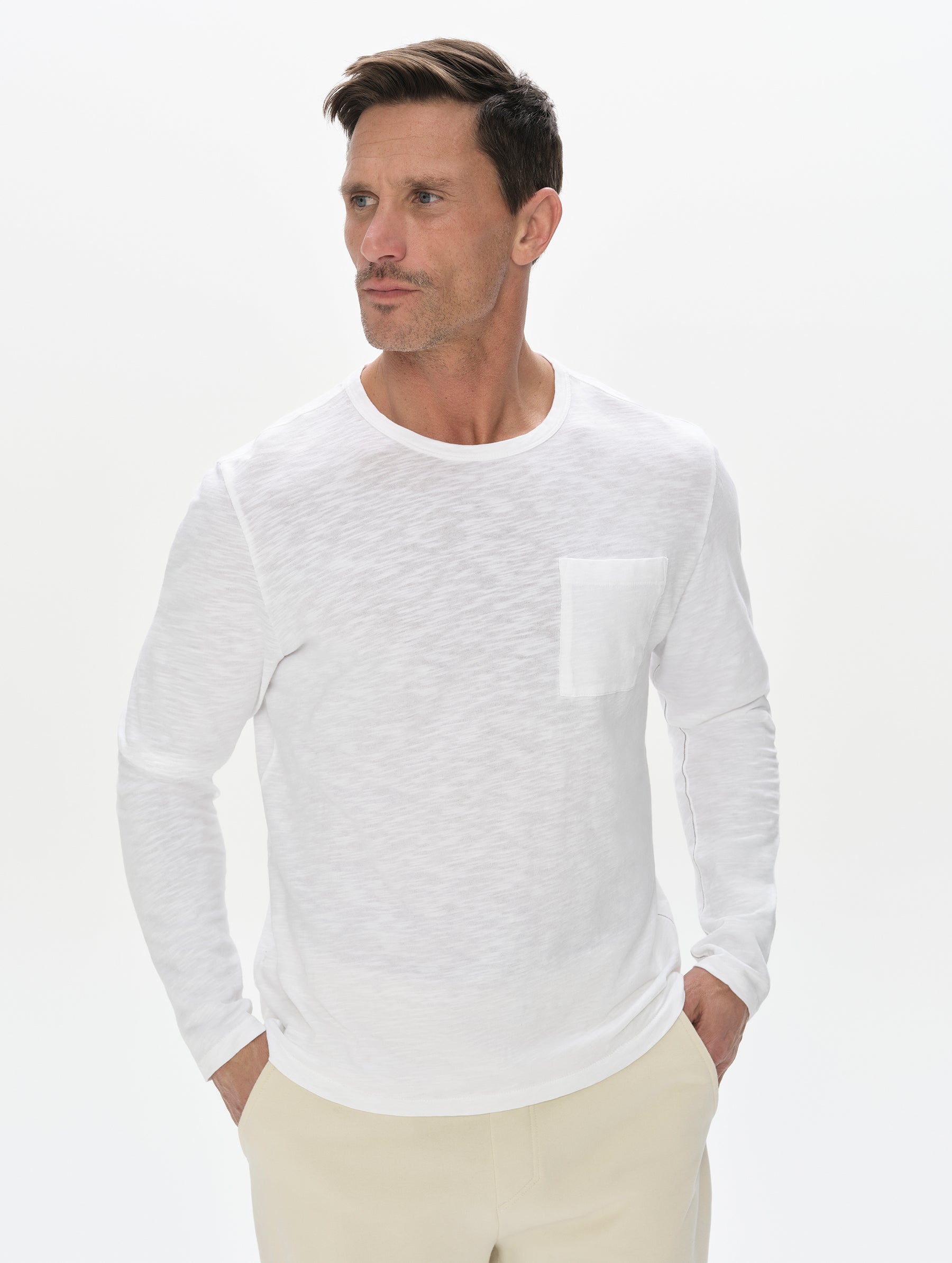 Front, upper-body view of man wearing Slub Long-Sleeve Pocket Tee 2.0 in White from AETHER Apparel.