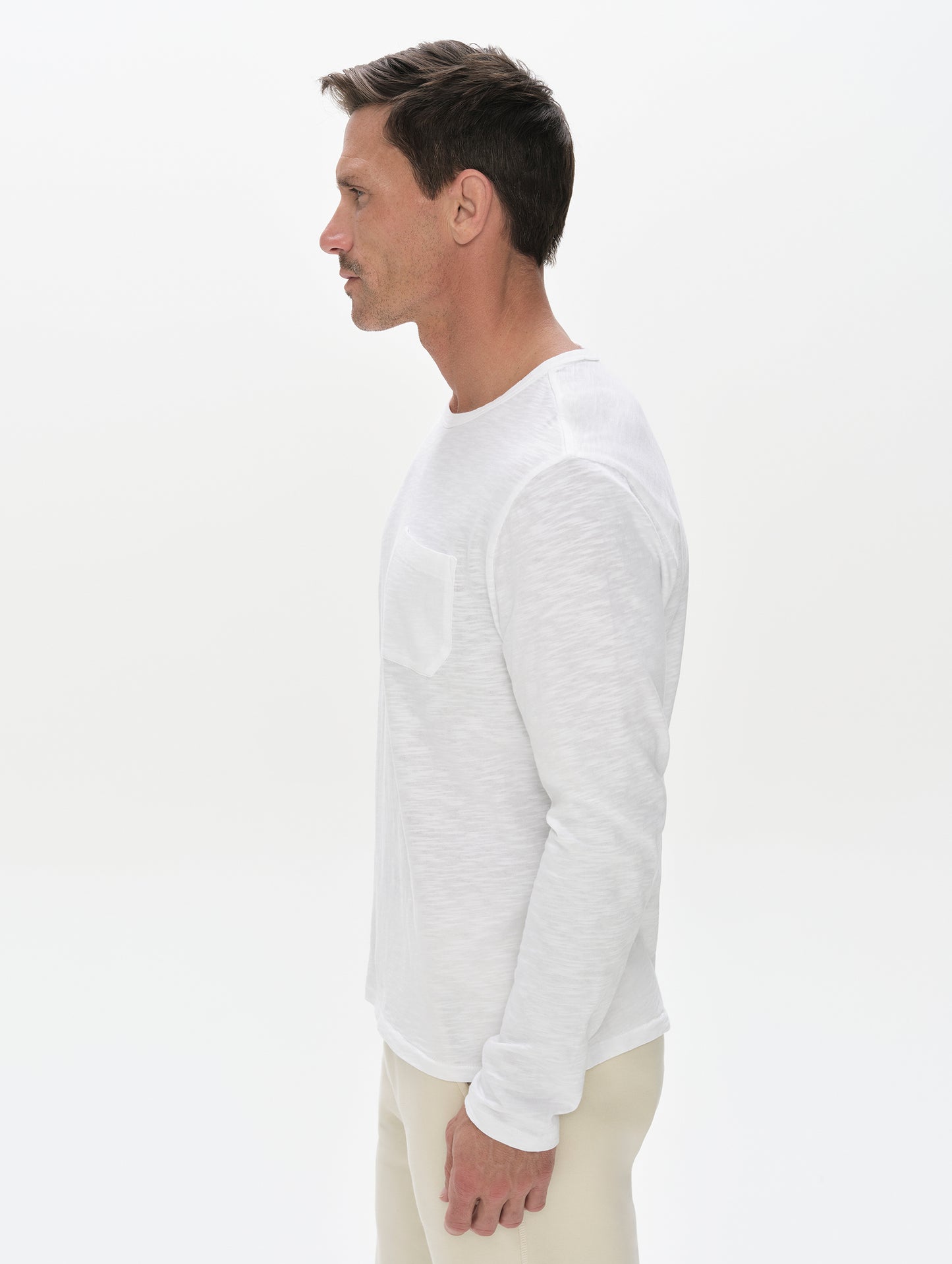 Side profile, upper-body view of man wearing Slub Long-Sleeve Pocket Tee 2.0 in White from AETHER Apparel.