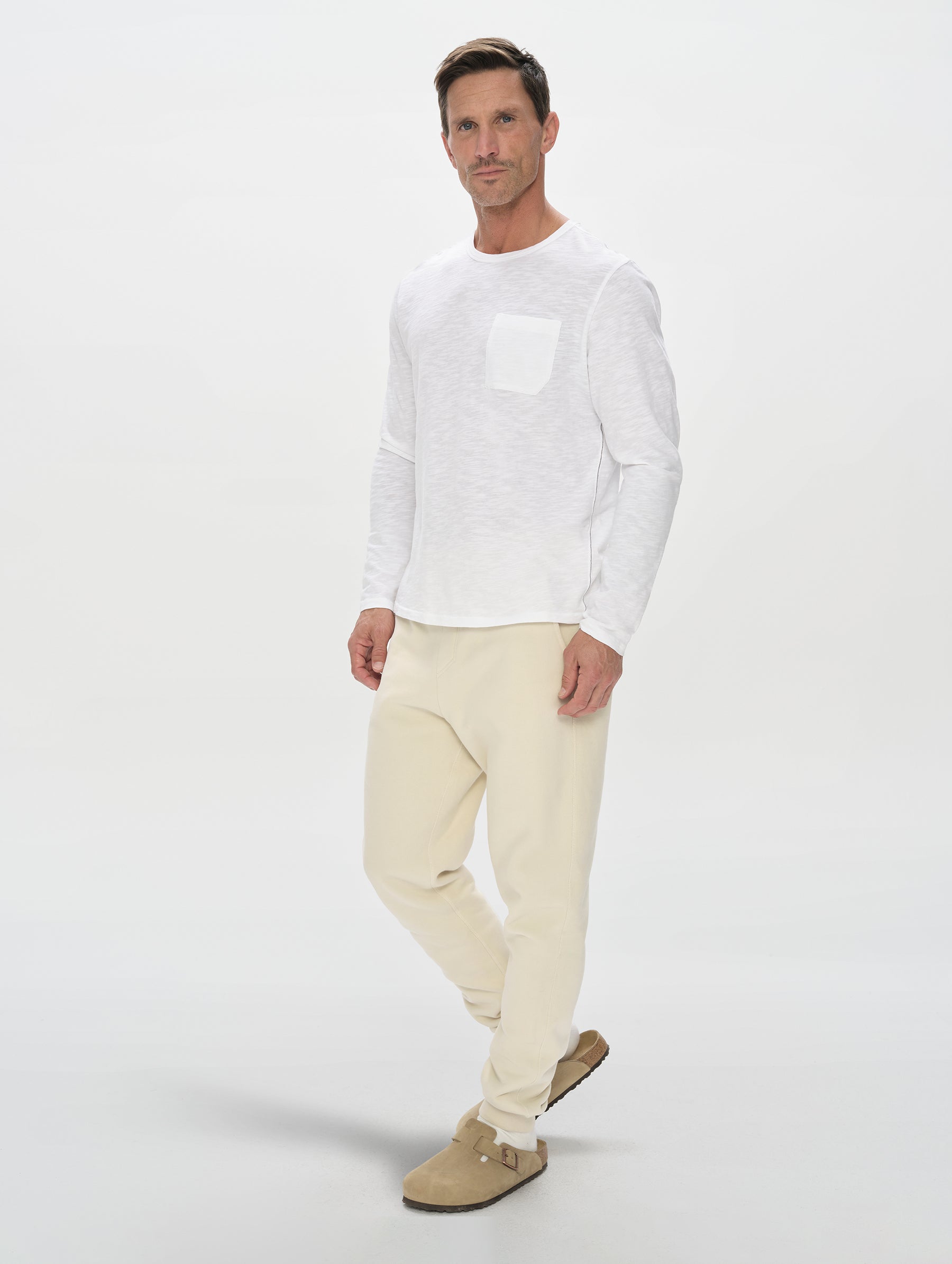 Front, full-body view of man wearing Slub Long-Sleeve Pocket Tee 2.0 in White from AETHER Apparel.