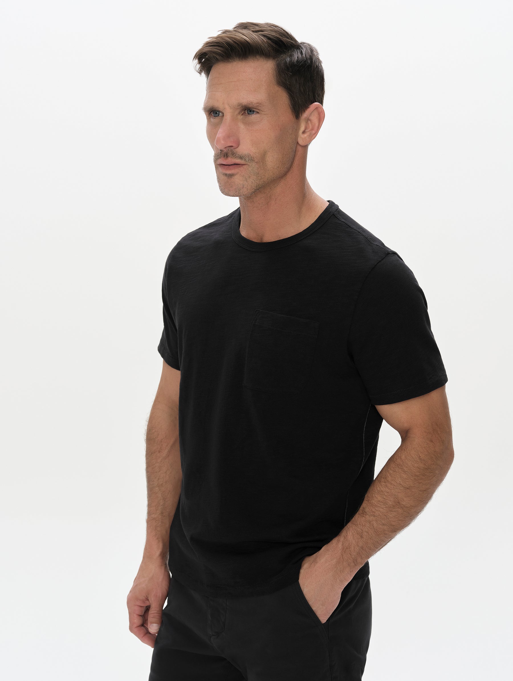 Front, 3/4, upper-body view of man wearing the Slub Pocket Tee 2.0 in Onyx Black from AETHER Apparel.