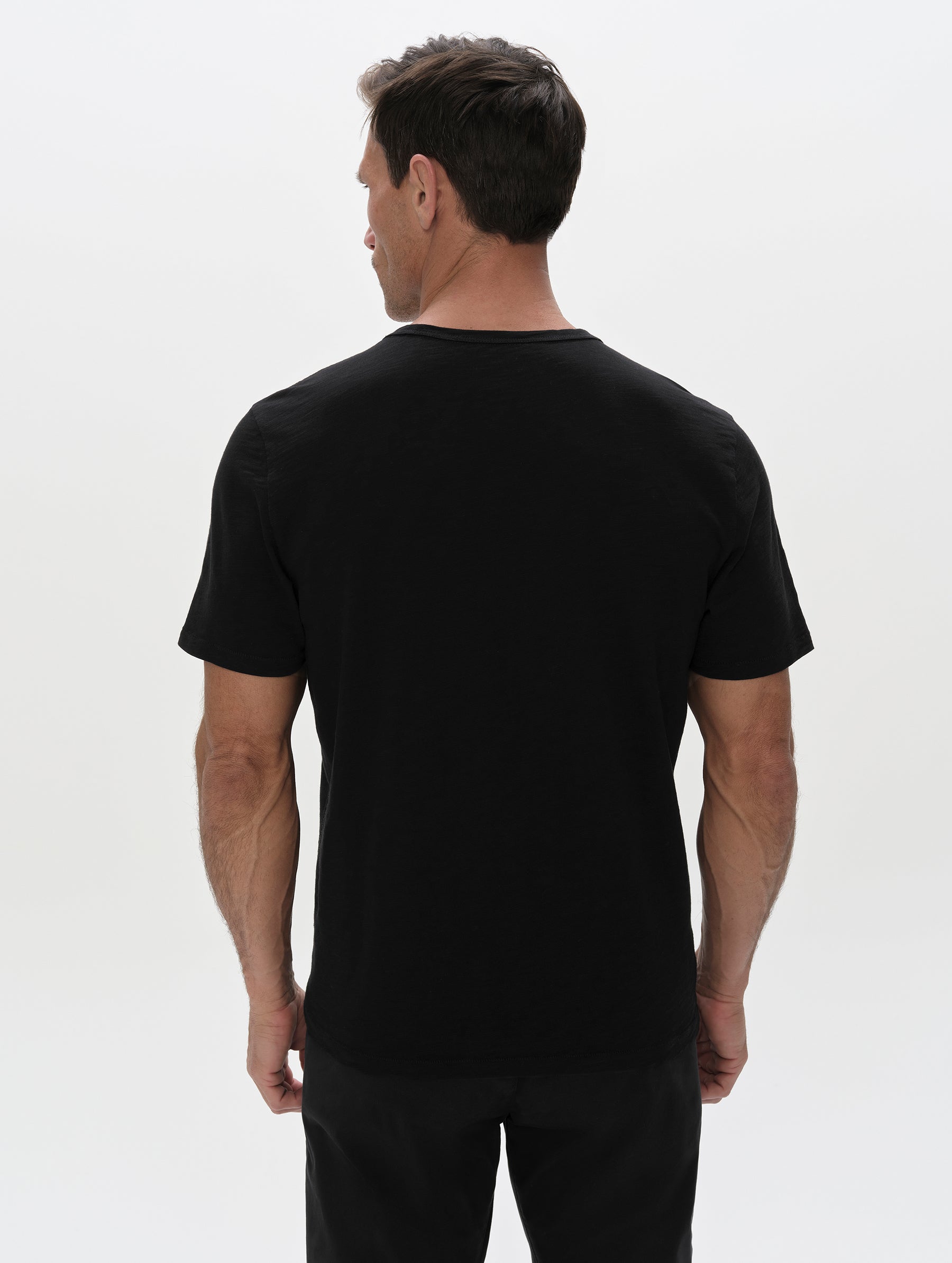 Rear, upper-body view of man wearing the Slub Pocket Tee 2.0 in Onyx Black from AETHER Apparel.